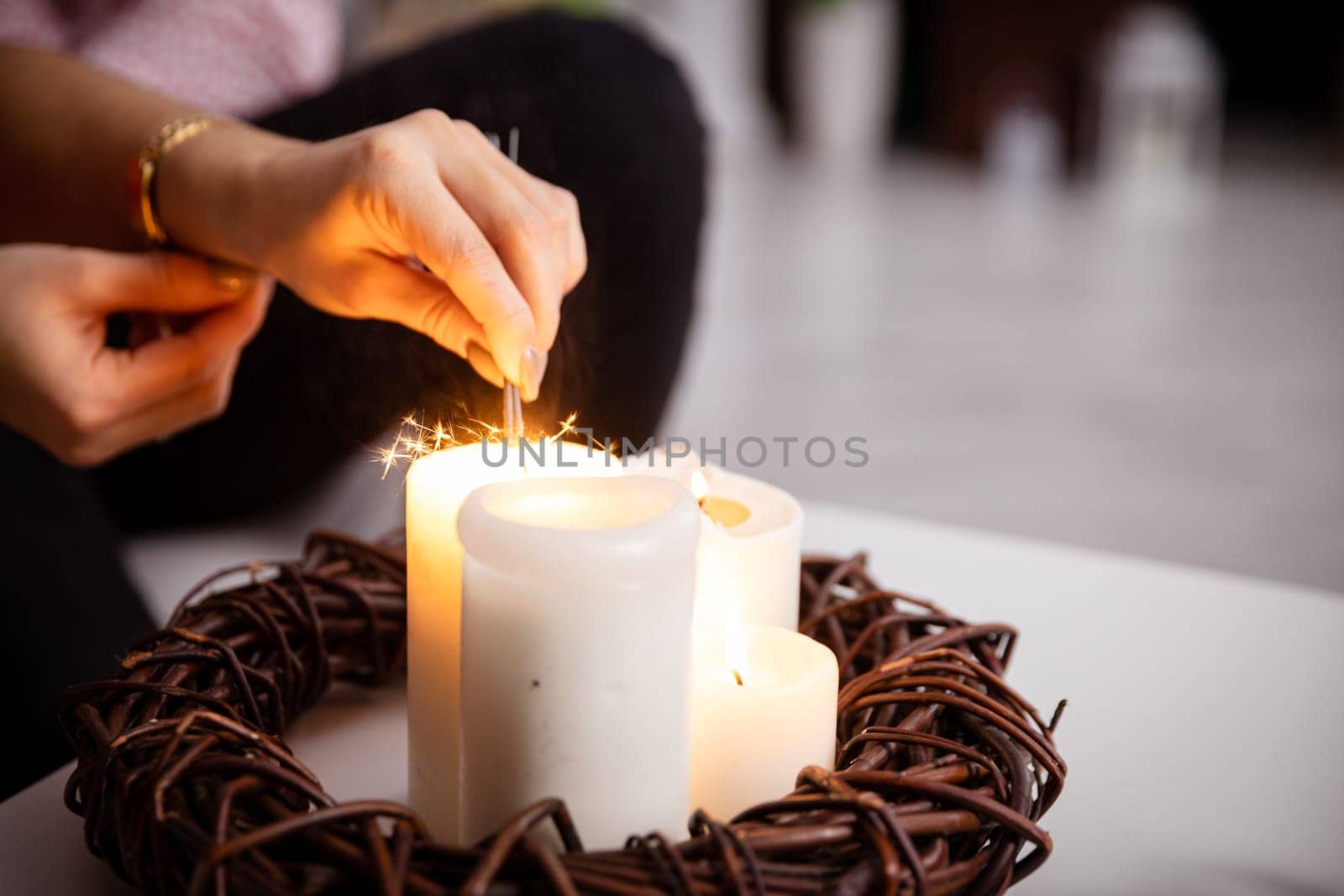 Four lit candles stand on the table as decoration and from them the girl lights fireworks. Romantic mood with burning candles.