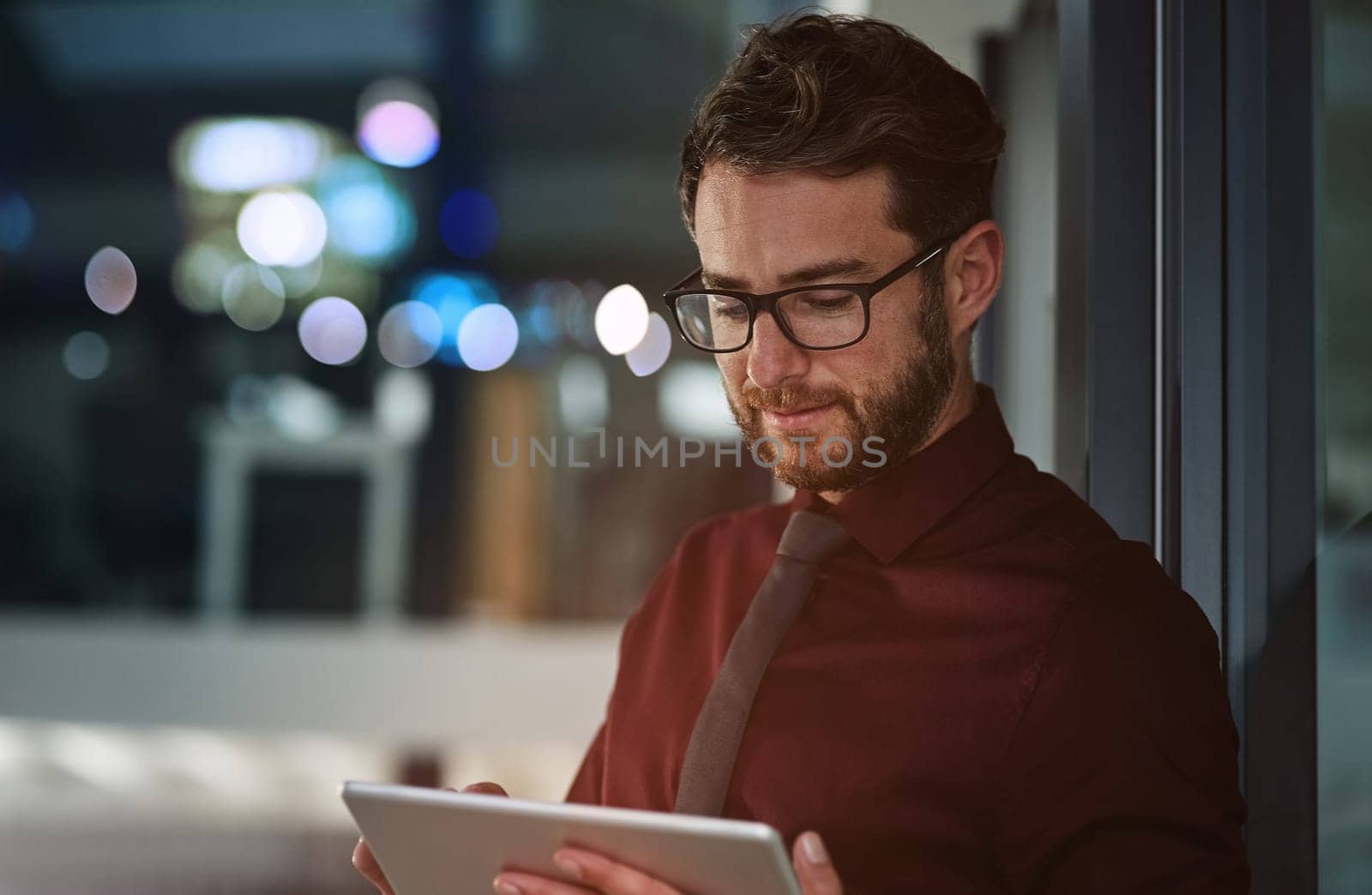 Loading his tablet with business apps. a young businessman using a digital tablet in a modern office