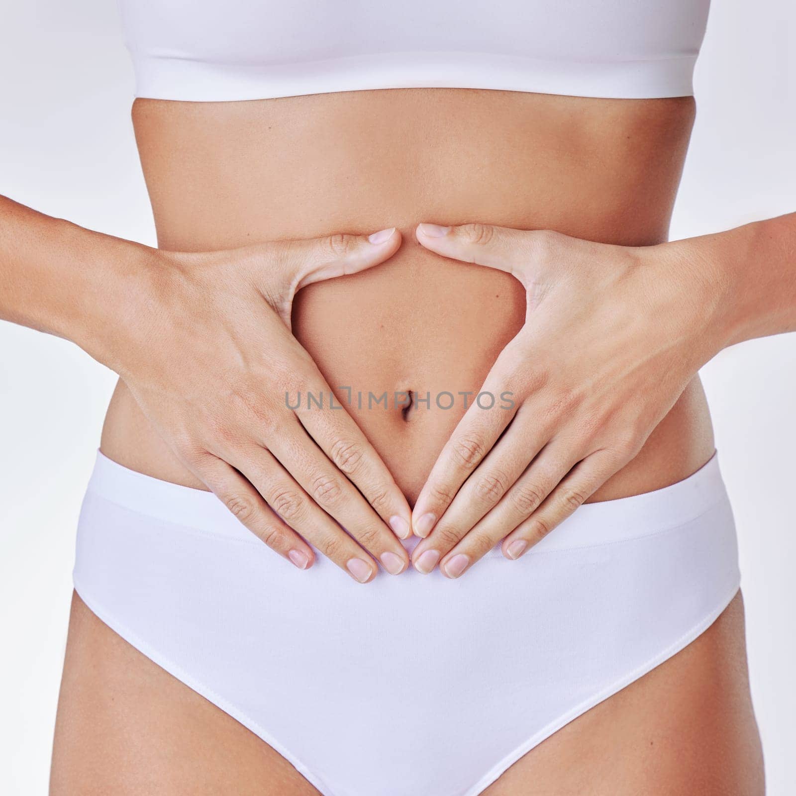 Hands heart, stomach and woman in studio showing gut health, wellness and weight loss. Digestion, female person and hand by abdomen with sign for healthy body care and fitness with white background.