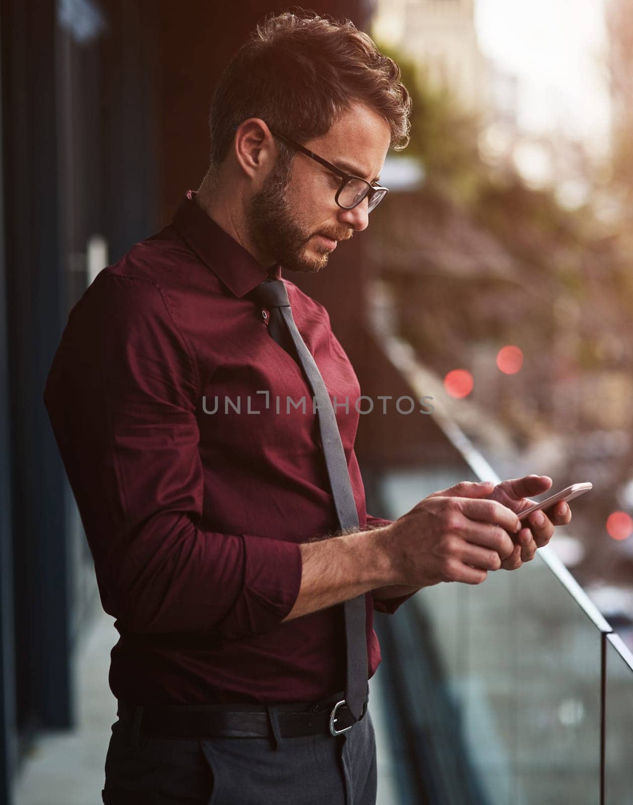Working that mobile business network. a young businessman using a mobile phone on the balcony of an office