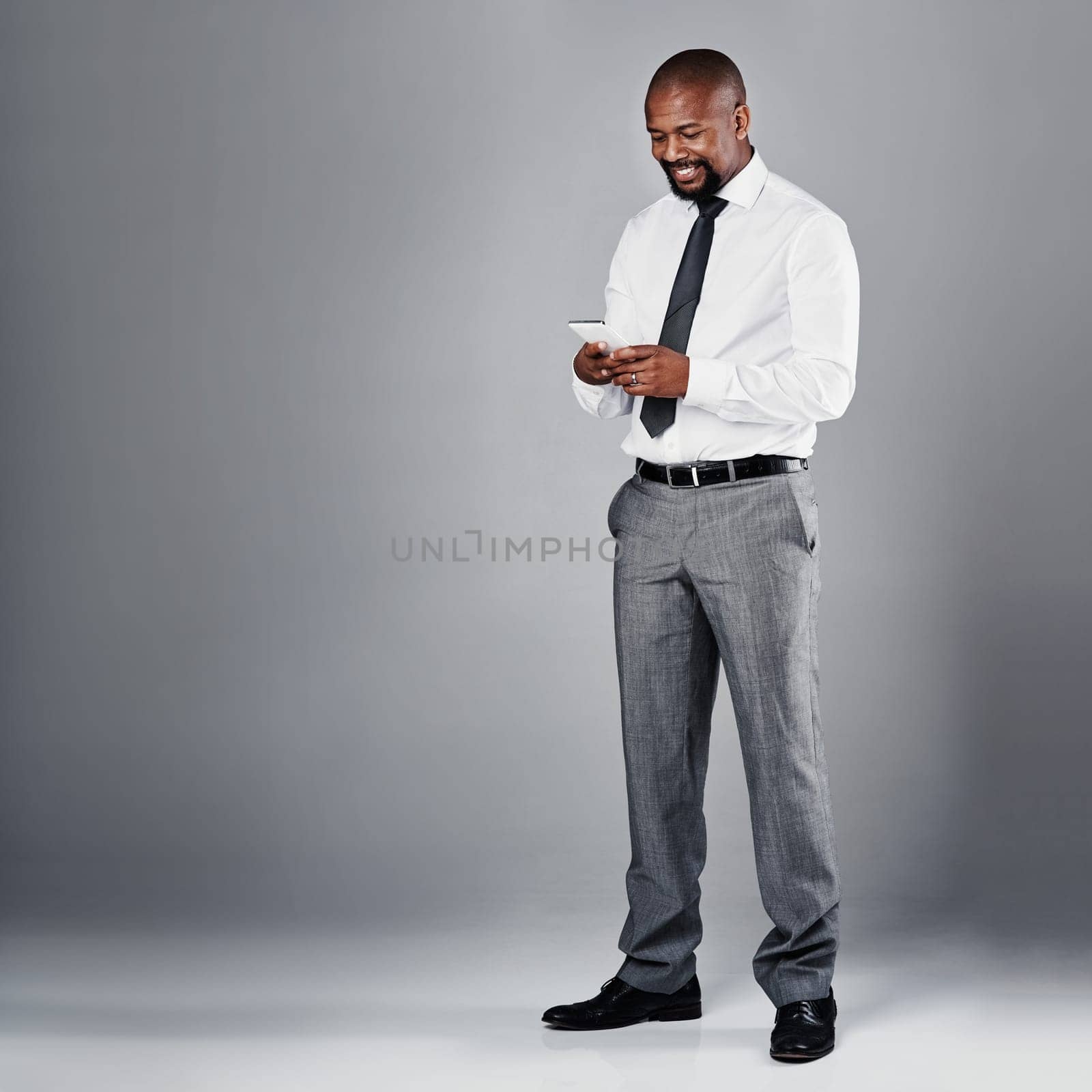 Gain an edge by mobilising your business. Studio shot of a corporate businessman texting on his against a grey background