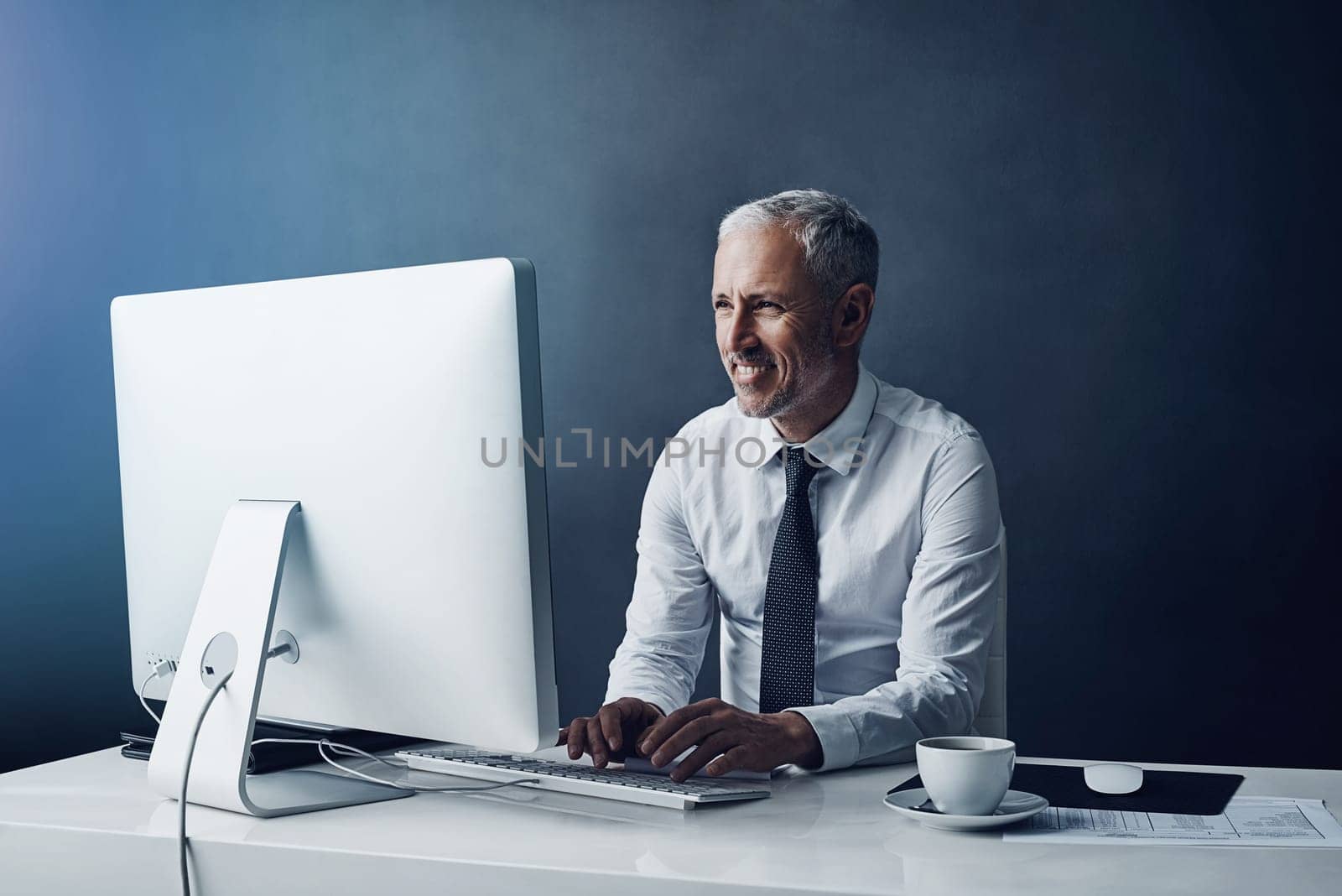 Working with a smile. a mature businessman working on his computer