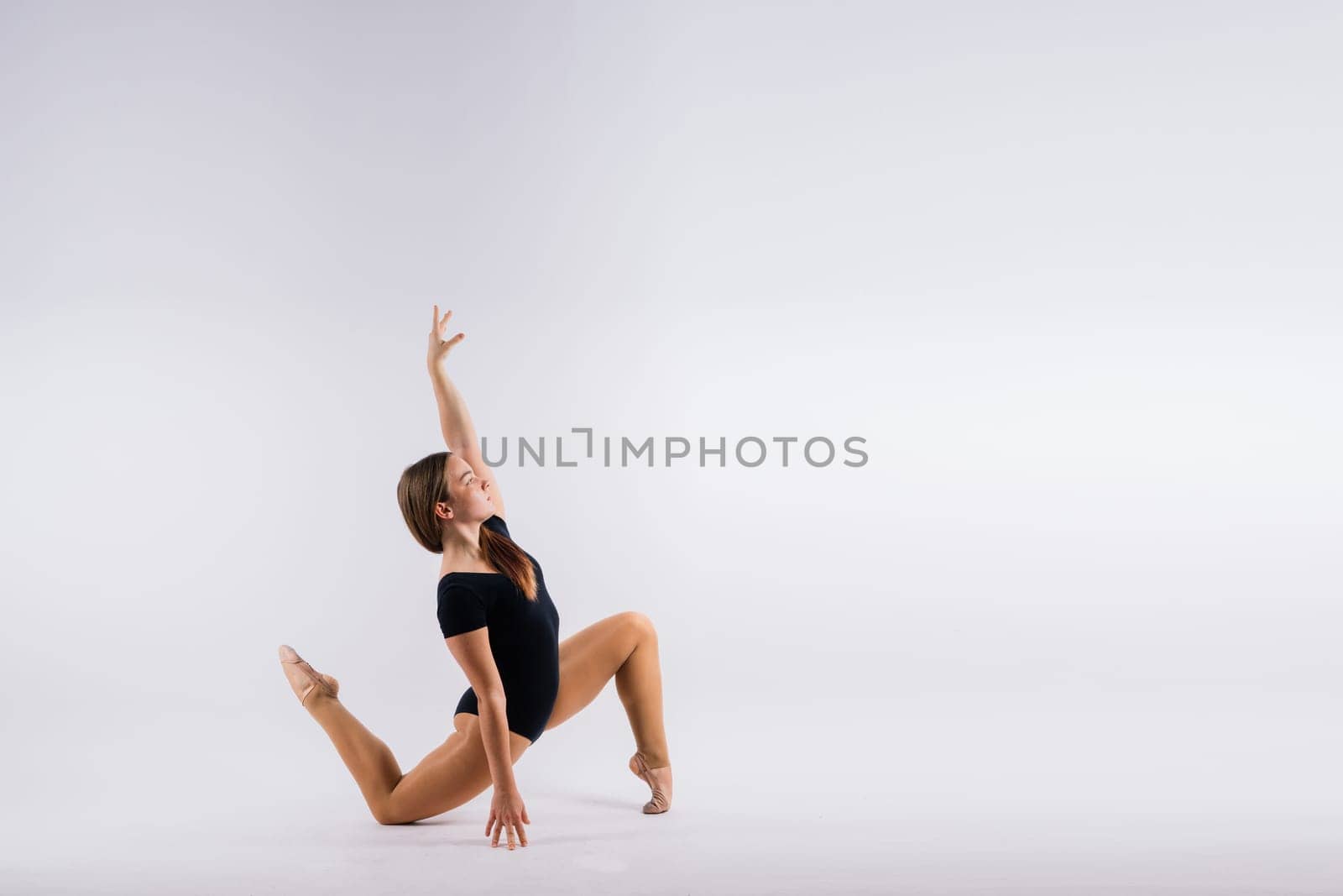 Sportive exercises, standing and stretching the hands. Beautiful muscular woman in indoors studio.