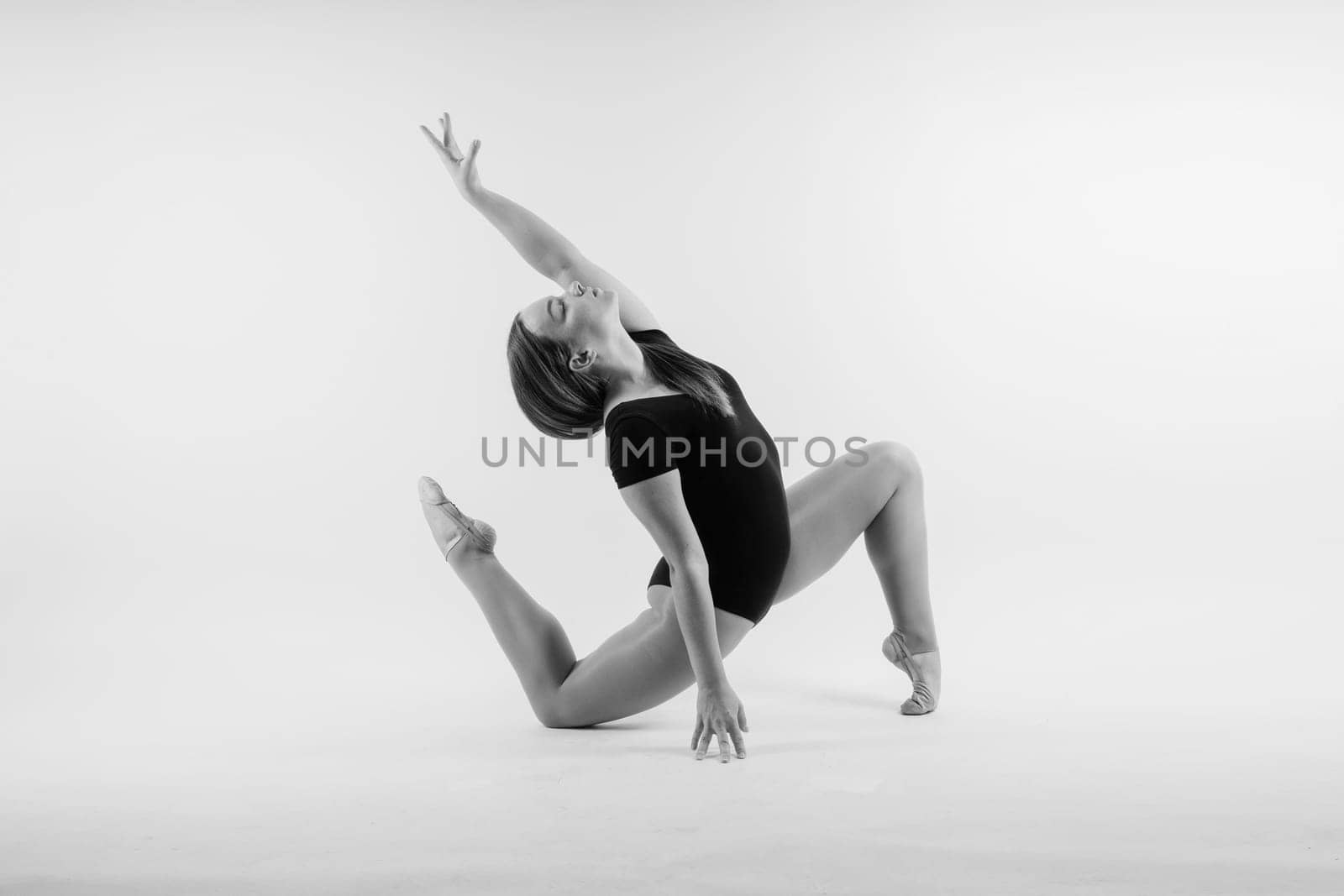 Sportive exercises, standing and stretching the hands. Beautiful muscular woman in indoors studio.