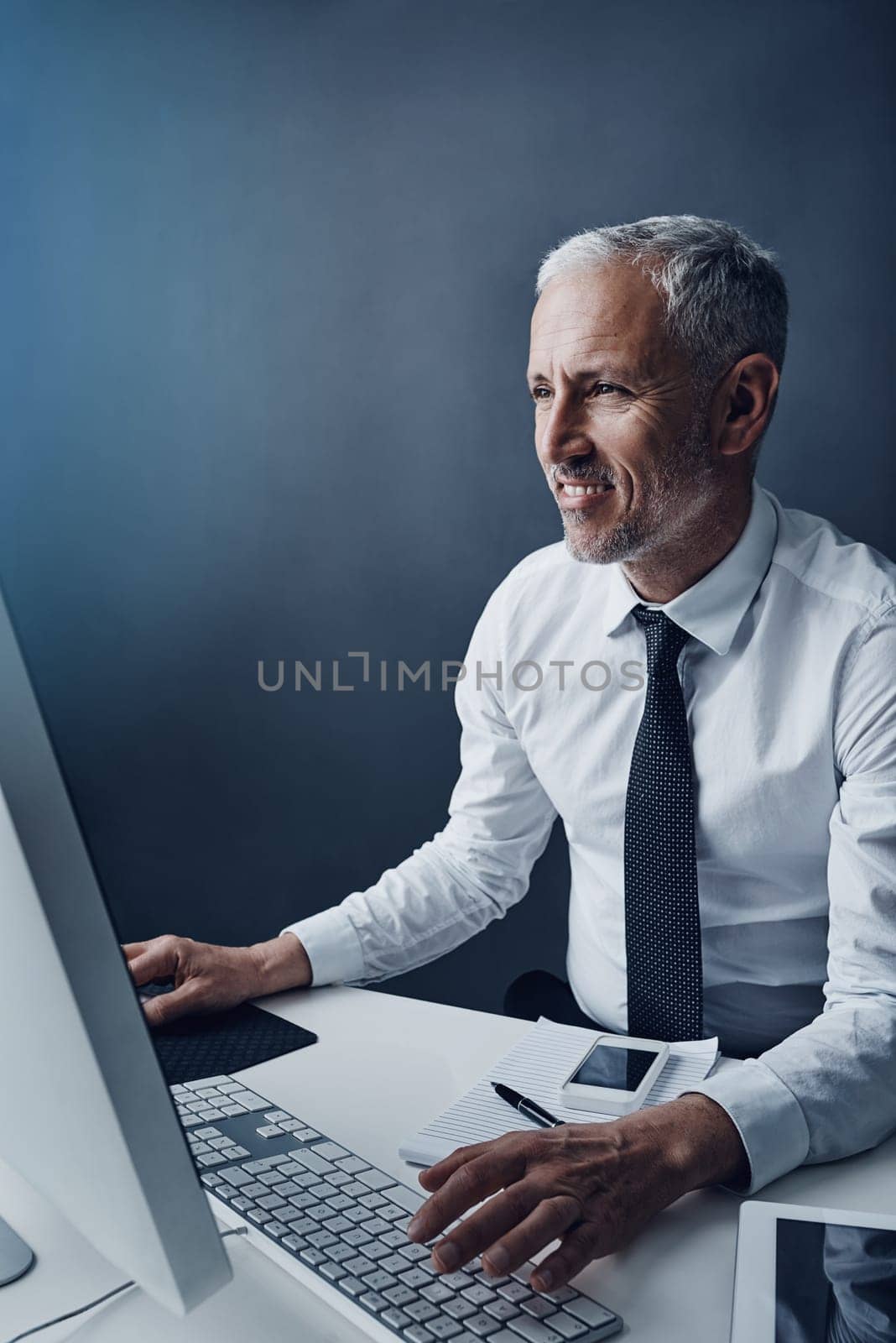 Progress is always positive. a mature businessman working on his computer. by YuriArcurs
