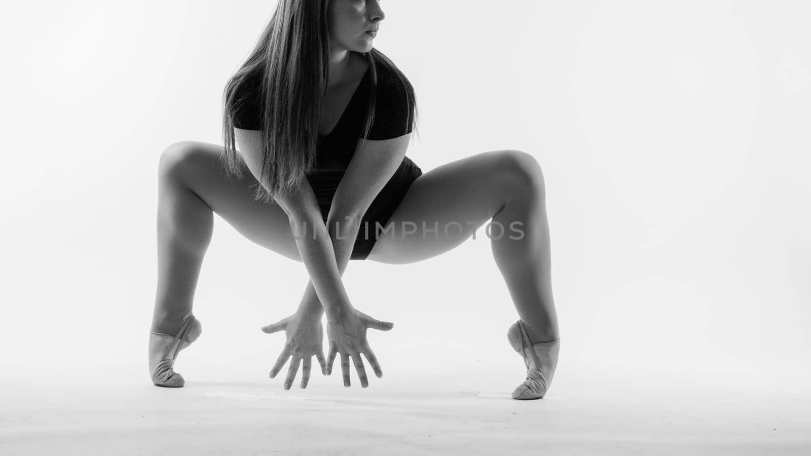 Sportive exercises, standing and stretching the hands. Beautiful muscular woman in indoors studio.