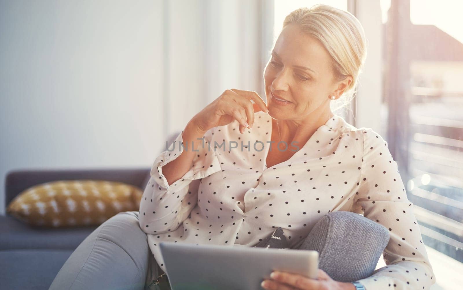 Reading some interesting news online. a mature woman using her digital tablet while relaxing at home