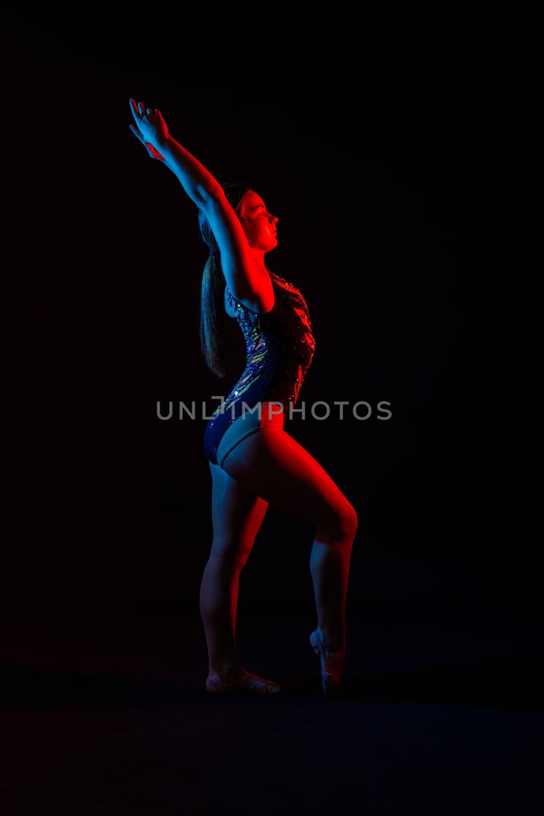 Sportive exercises, standing and stretching the hands. Beautiful muscular woman in indoors studio.