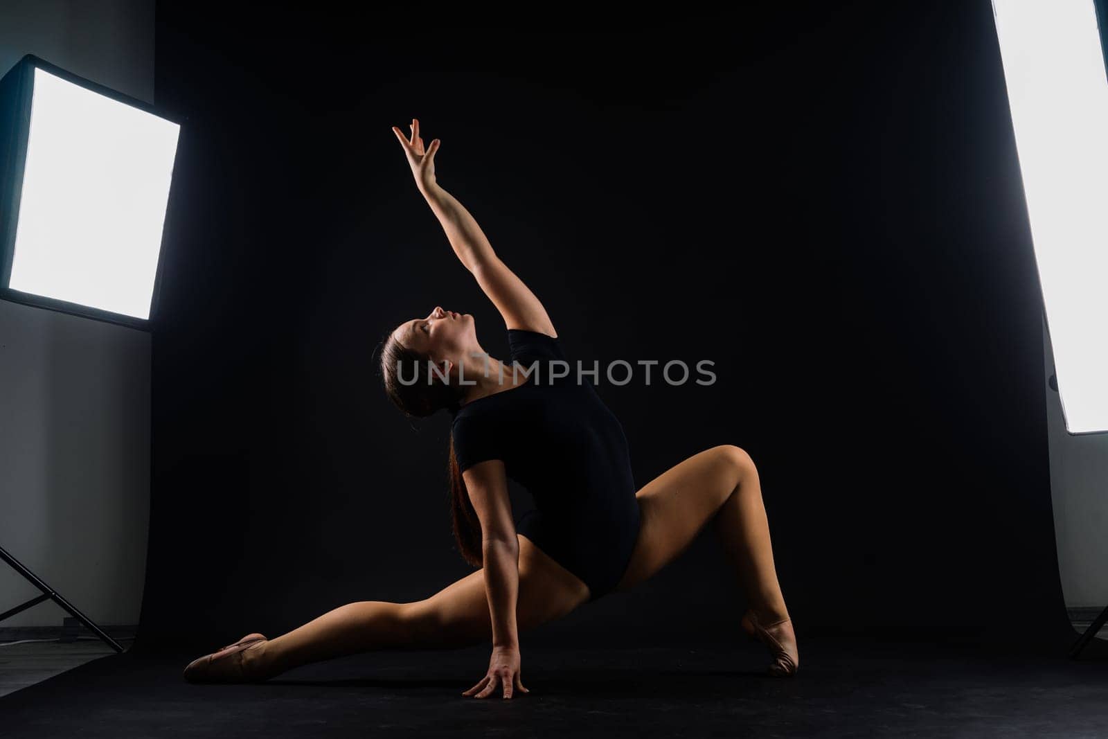 Sportive exercises, standing and stretching the hands. Beautiful muscular woman in indoors studio.