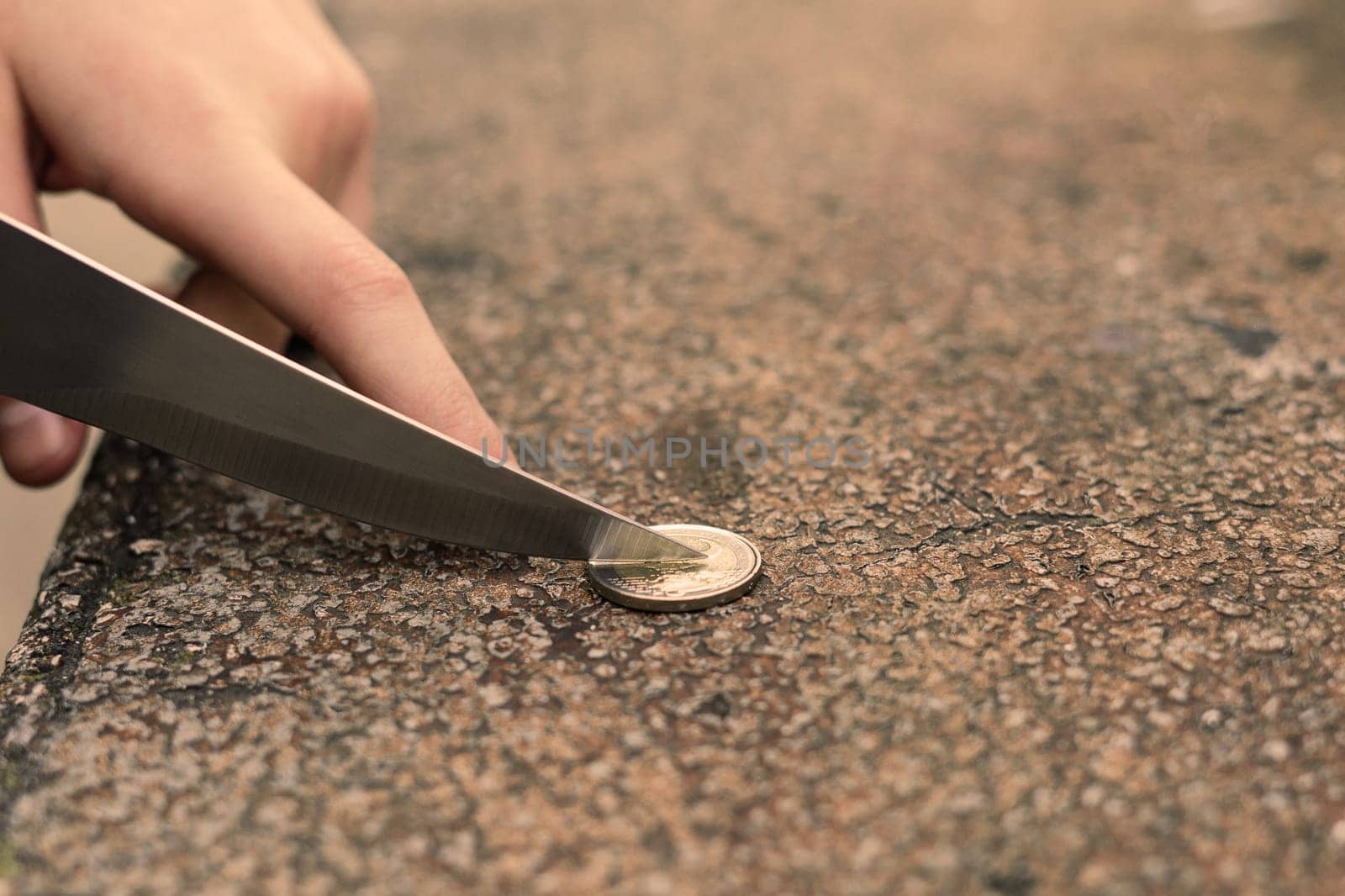 Knife blade on euro coin. Concept for cutting rates, money business, crime. Macro, selective focus. by Zelenin