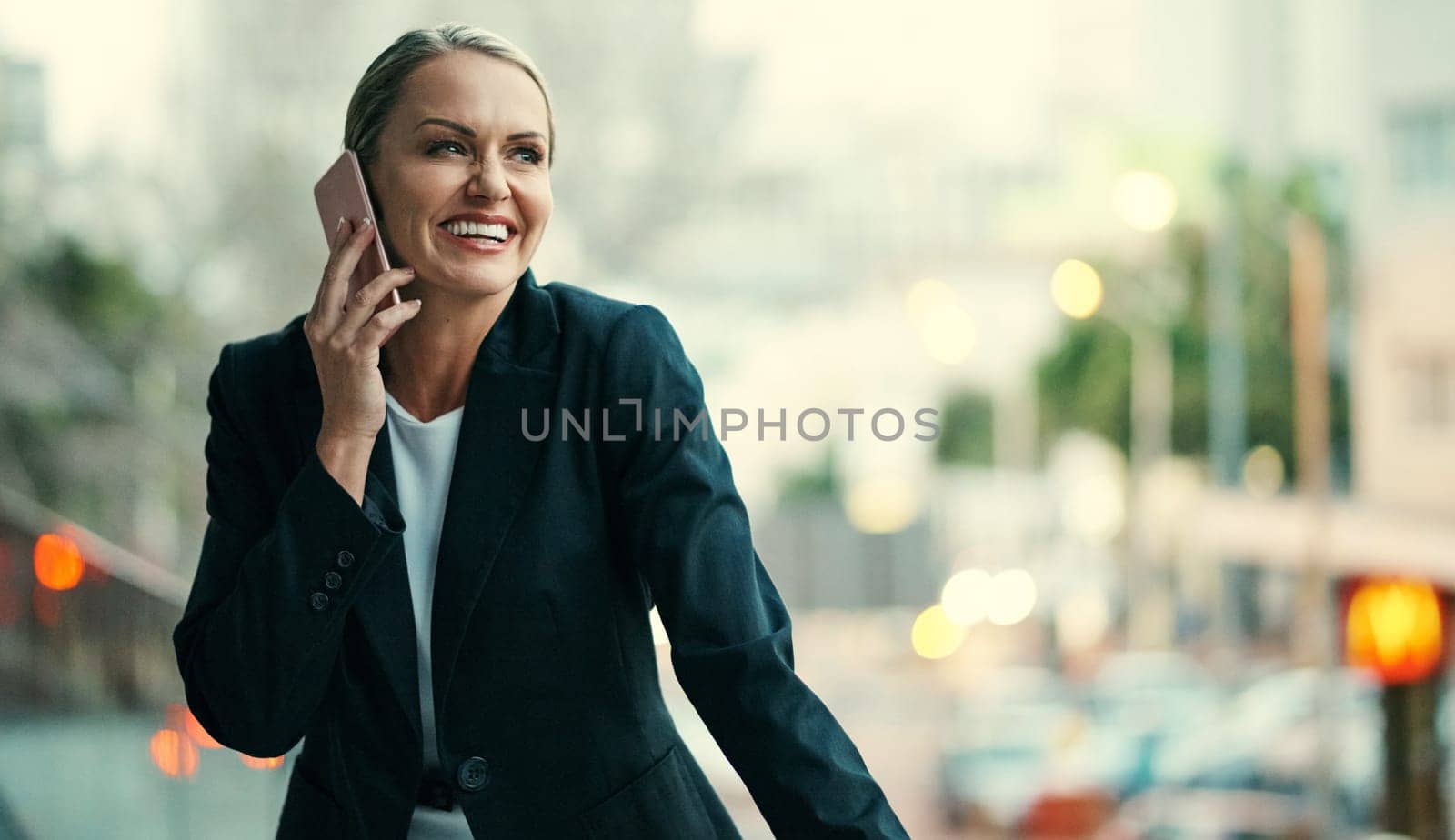 Thats great news. an attractive mature businesswoman using her cellphone while standing on the balcony of her office