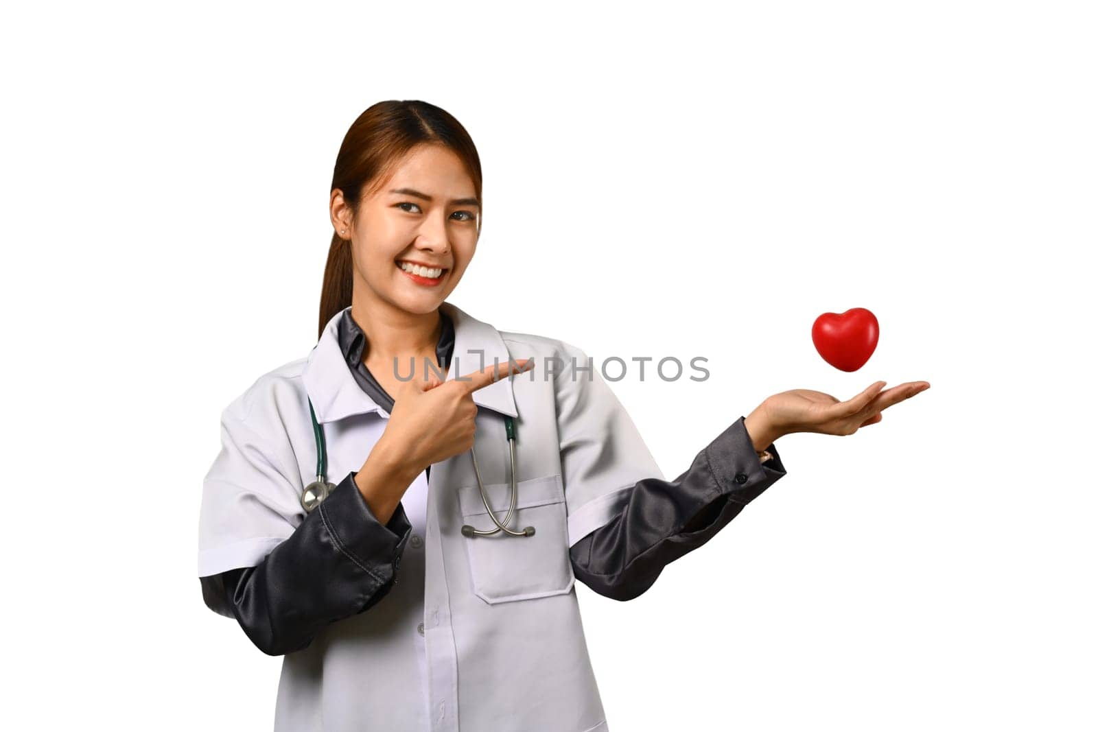 Smiling female doctor cardiologist holding and pointing at red heart. Cardiology, medicine, donation and healthcare concept.