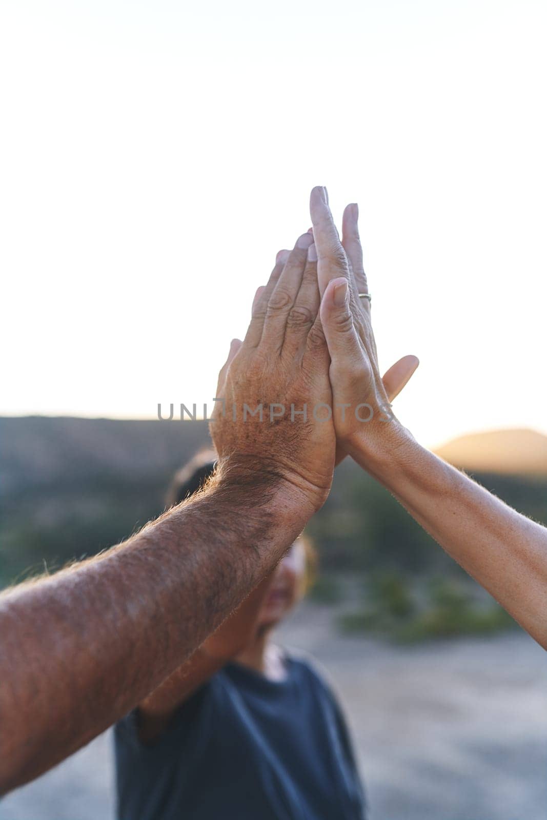 A bond thats so strong cant be broken. a family joining their hands in solidarity outdoors. by YuriArcurs