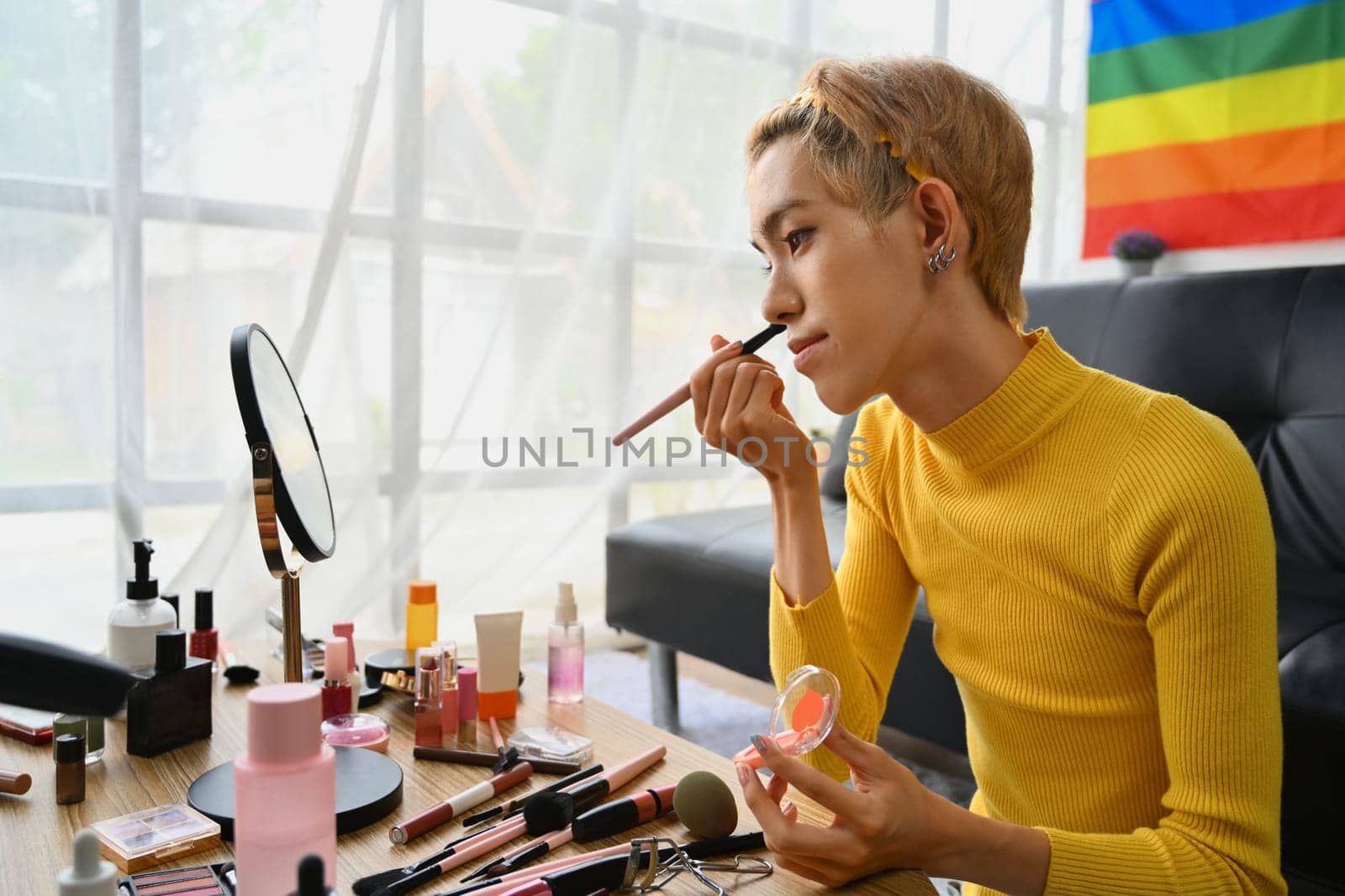 Smiling Asian gay man blogger filming daily makeup routine tutorial on smartphone. LGBTQ, domestic life and beauty concept.