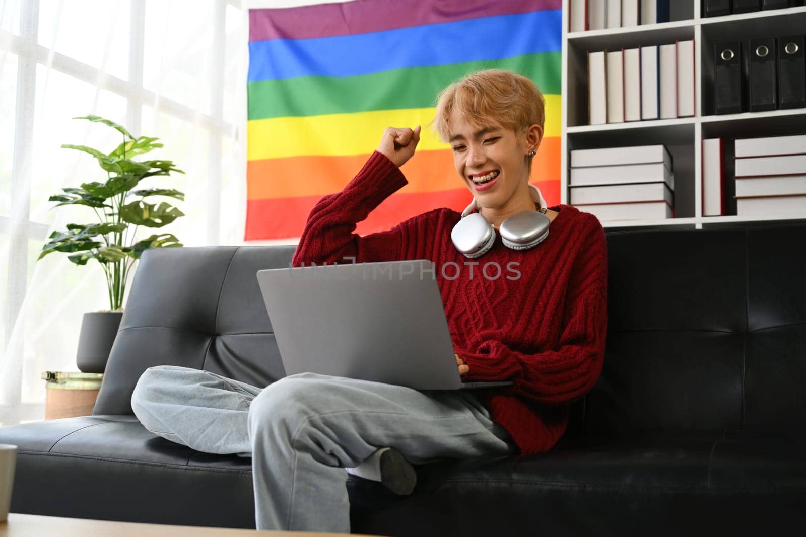 Excited happy young gay man student read great news online on laptop and celebrating, receiving good test results or admission.