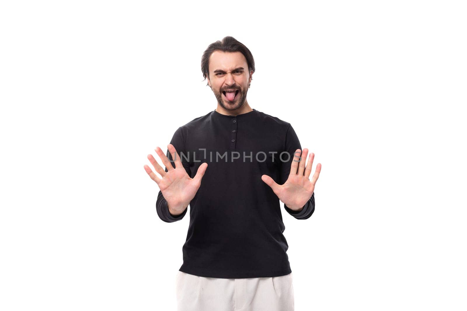 young confused handsome brunet european man in black sweatshirt on isolated white background by TRMK