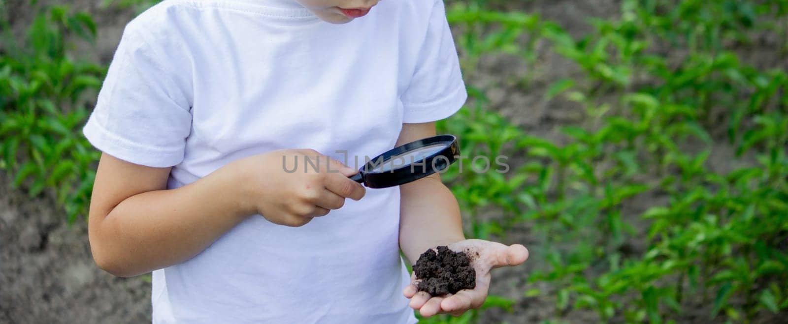 the child holds the earth in his hand and looks through a magnifying glass. Selective focus