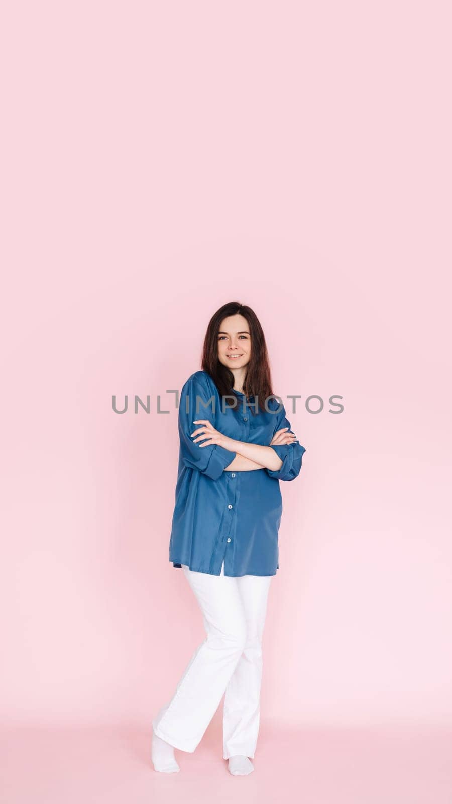 Confident businesswoman in stylish smart casual outfit, standing with folded hands, isolated on pink background, full body shot, Vertical photography by ViShark