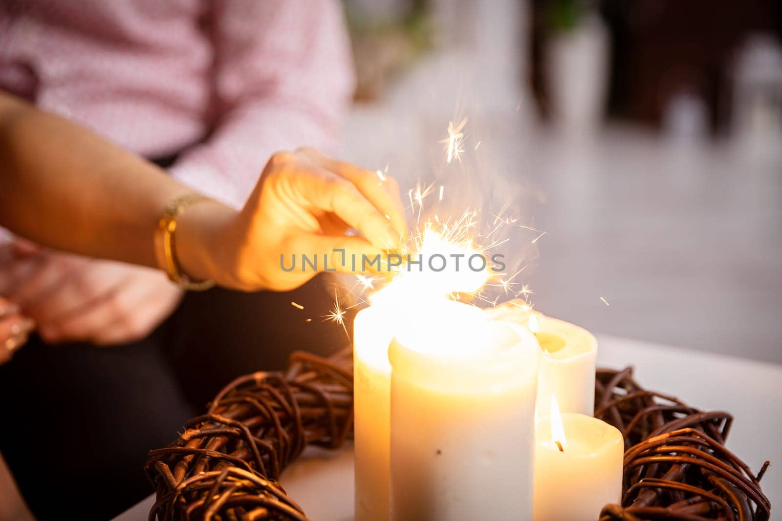 A girl from the fire of a candle standing on a table lights fireworks. by fotodrobik