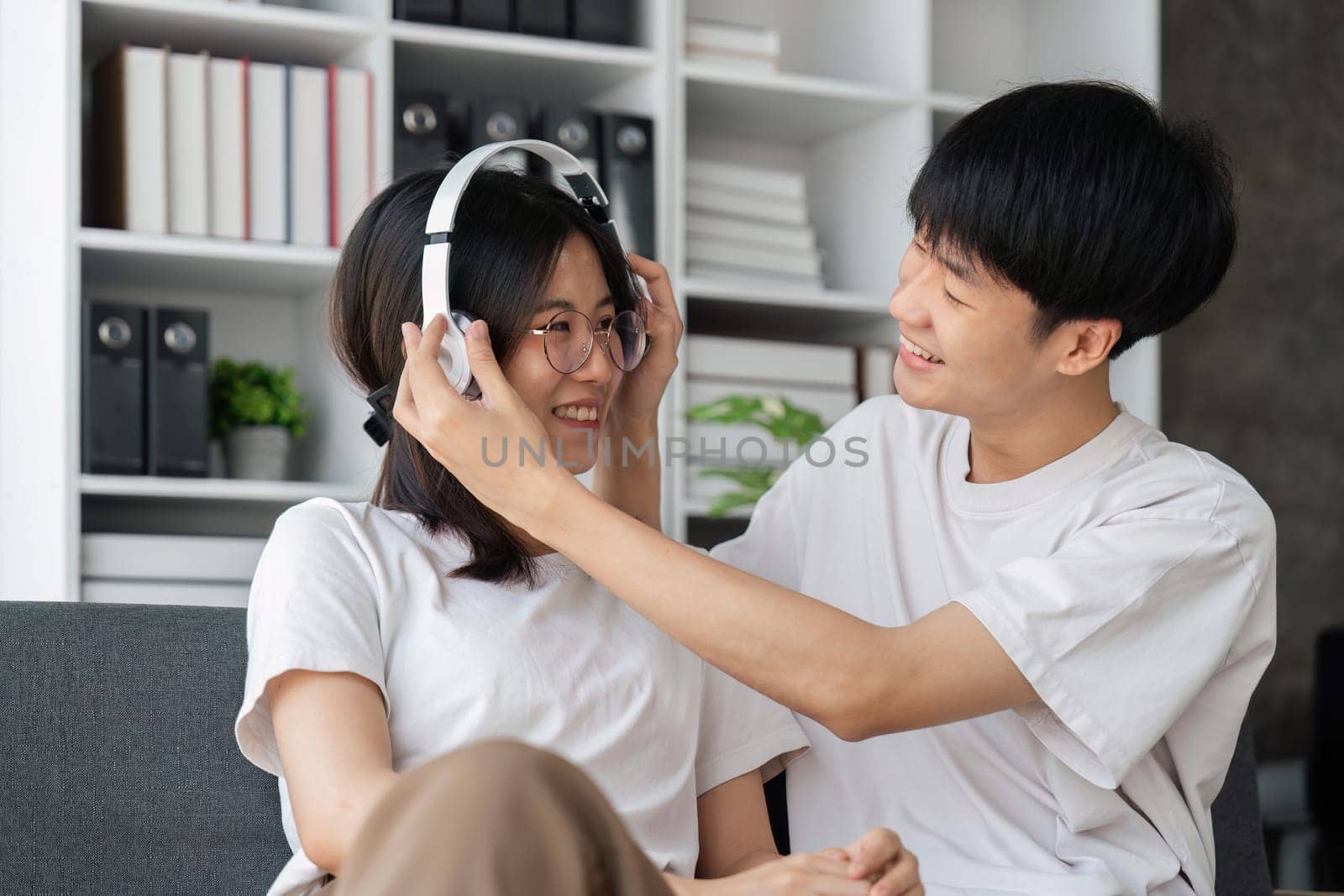 Activity at home concept, couple wears headphone to girlfriend and listening music together by nateemee