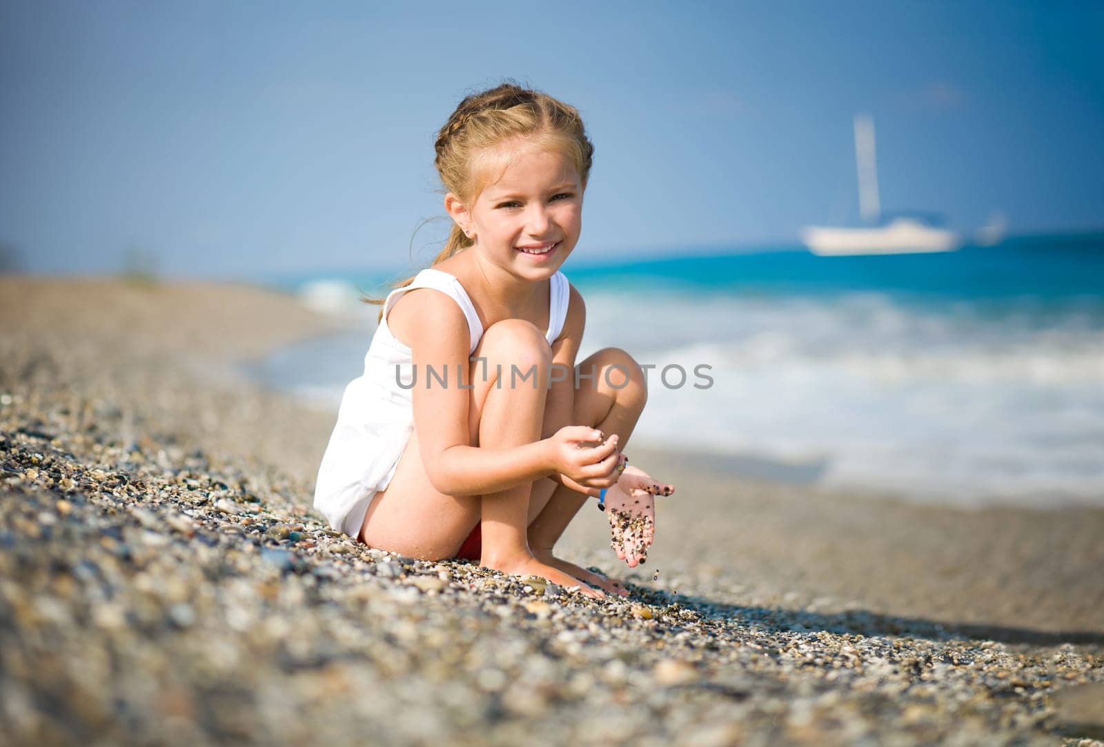 girl with pebbles in her hands on the beach