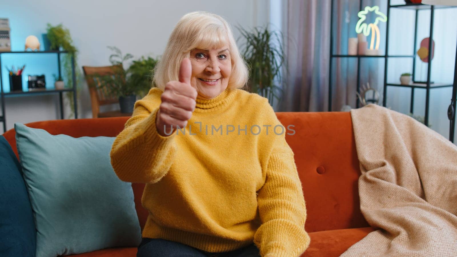 Like. Happy excited senior woman looking approvingly at camera showing thumbs up, like sign positive something, good great news, positive feedback. Elderly grandmother sitting on couch at home room