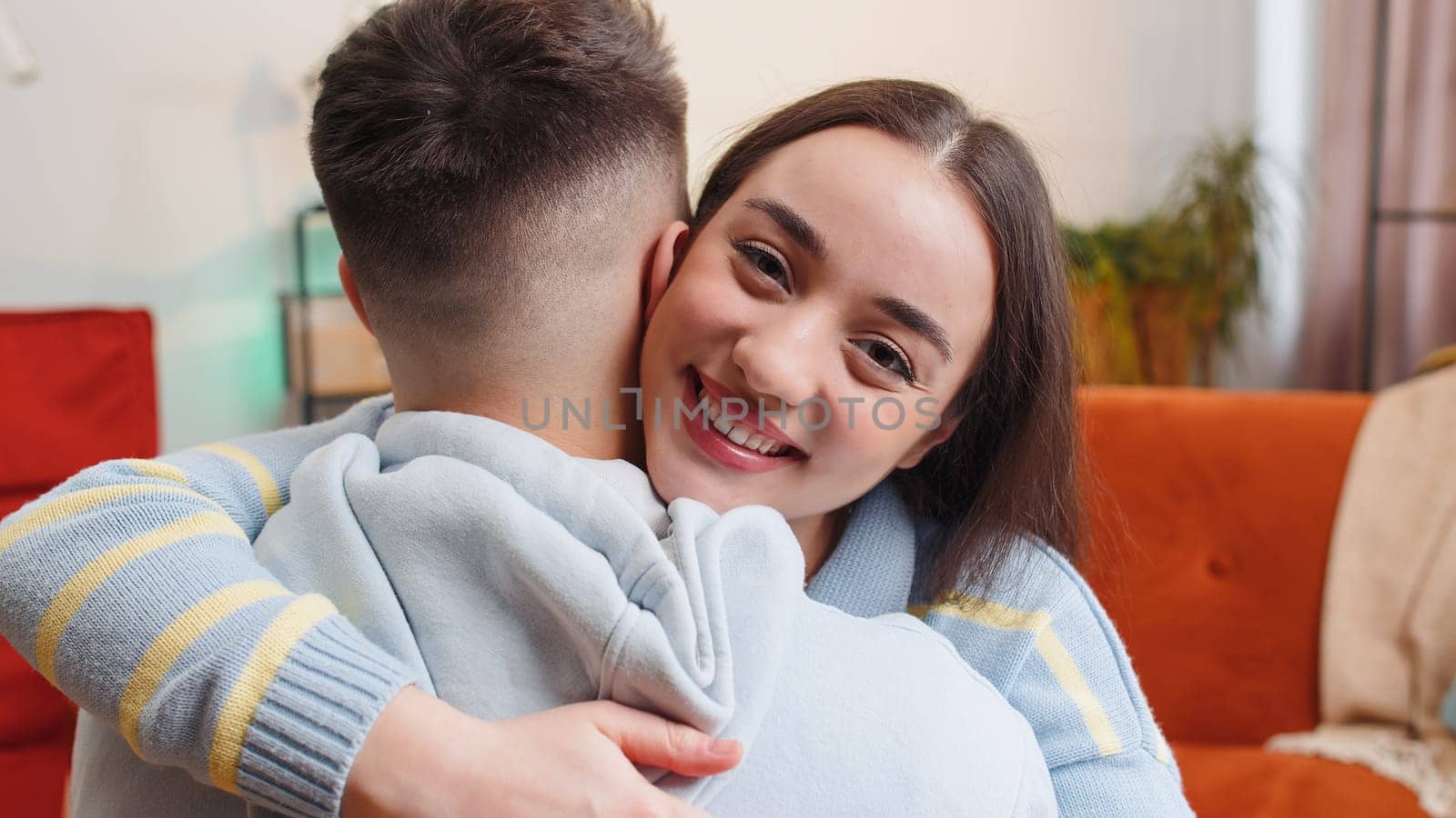 Portrait of woman embracing, hugging man, looking at camera over his shoulder at home room, support by efuror