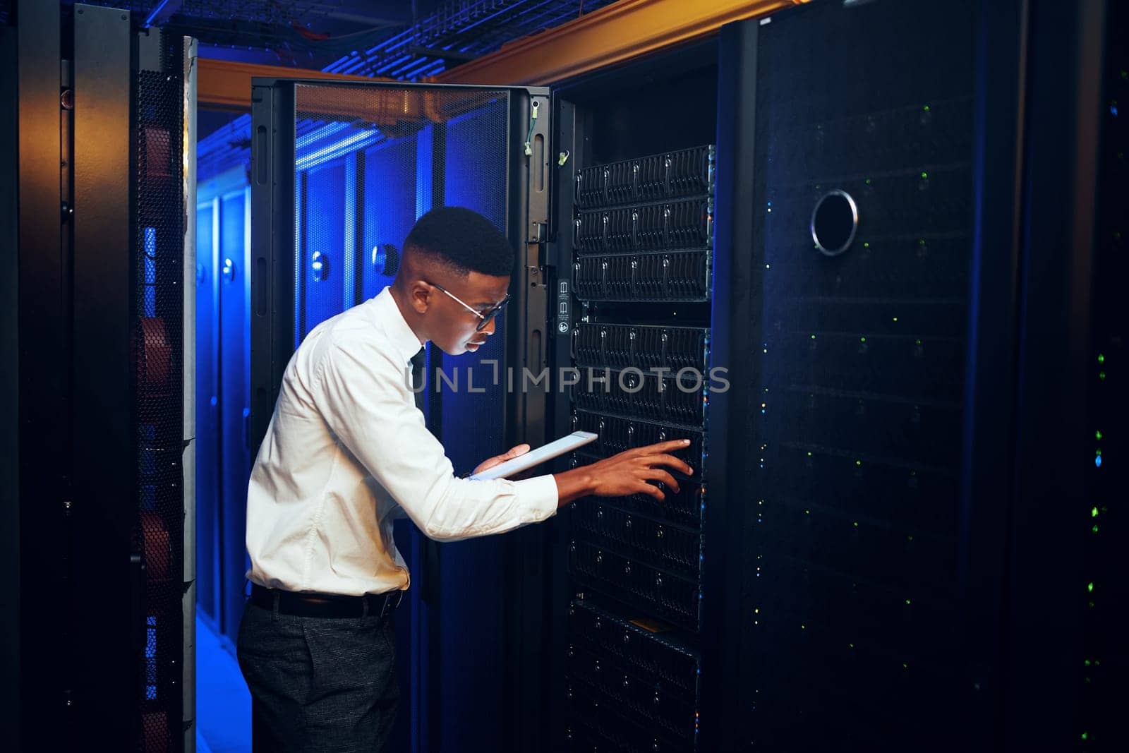 Going about the days inspections. a young man using a digital tablet while working in a server room