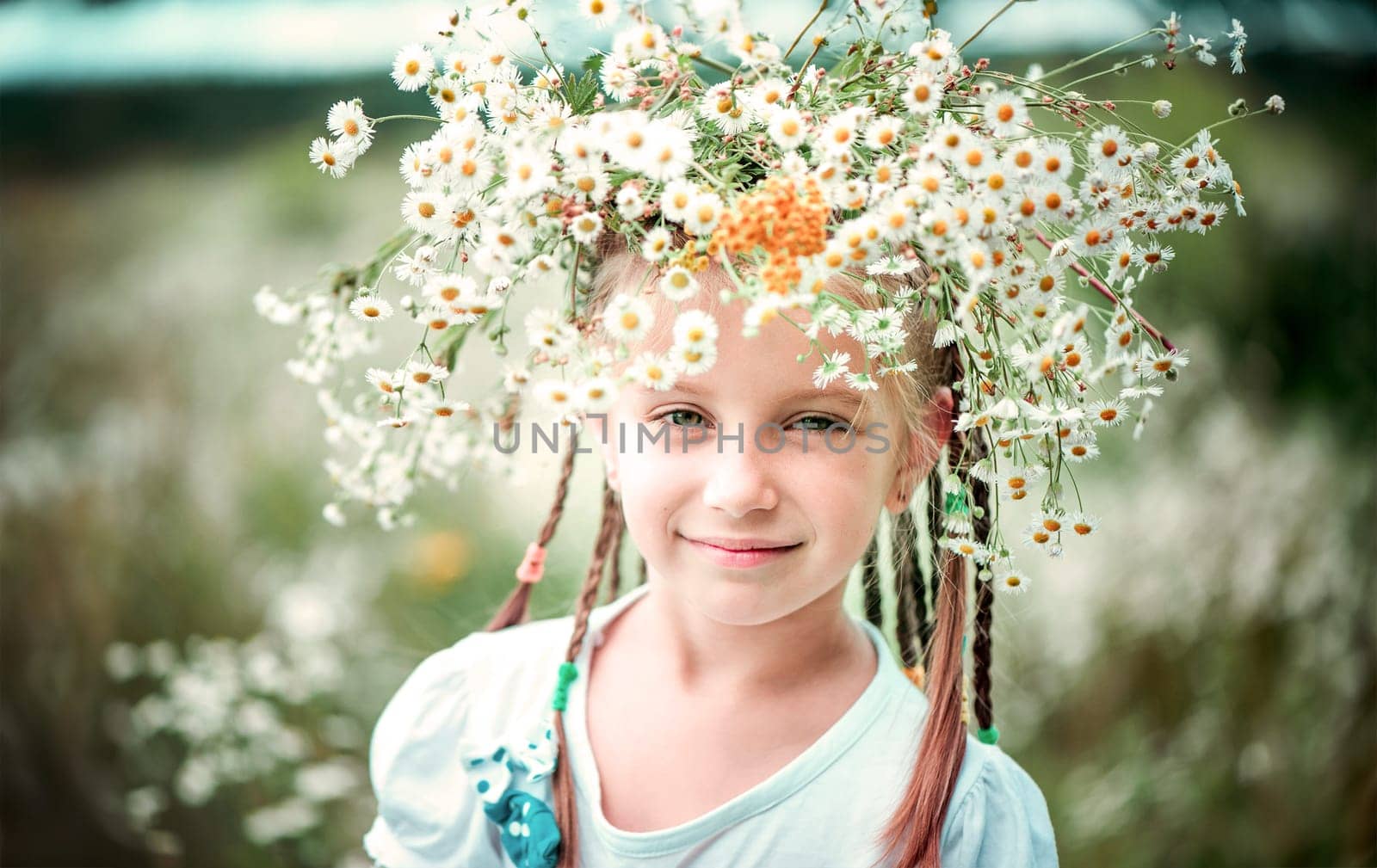six year old girl with a wreath on her head on the field with chamomiles