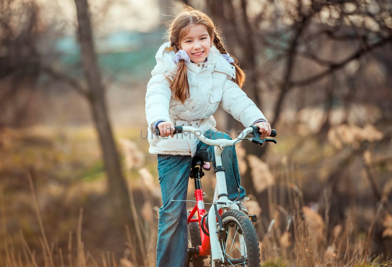 Happy cute little girl on a bicycle in the spring