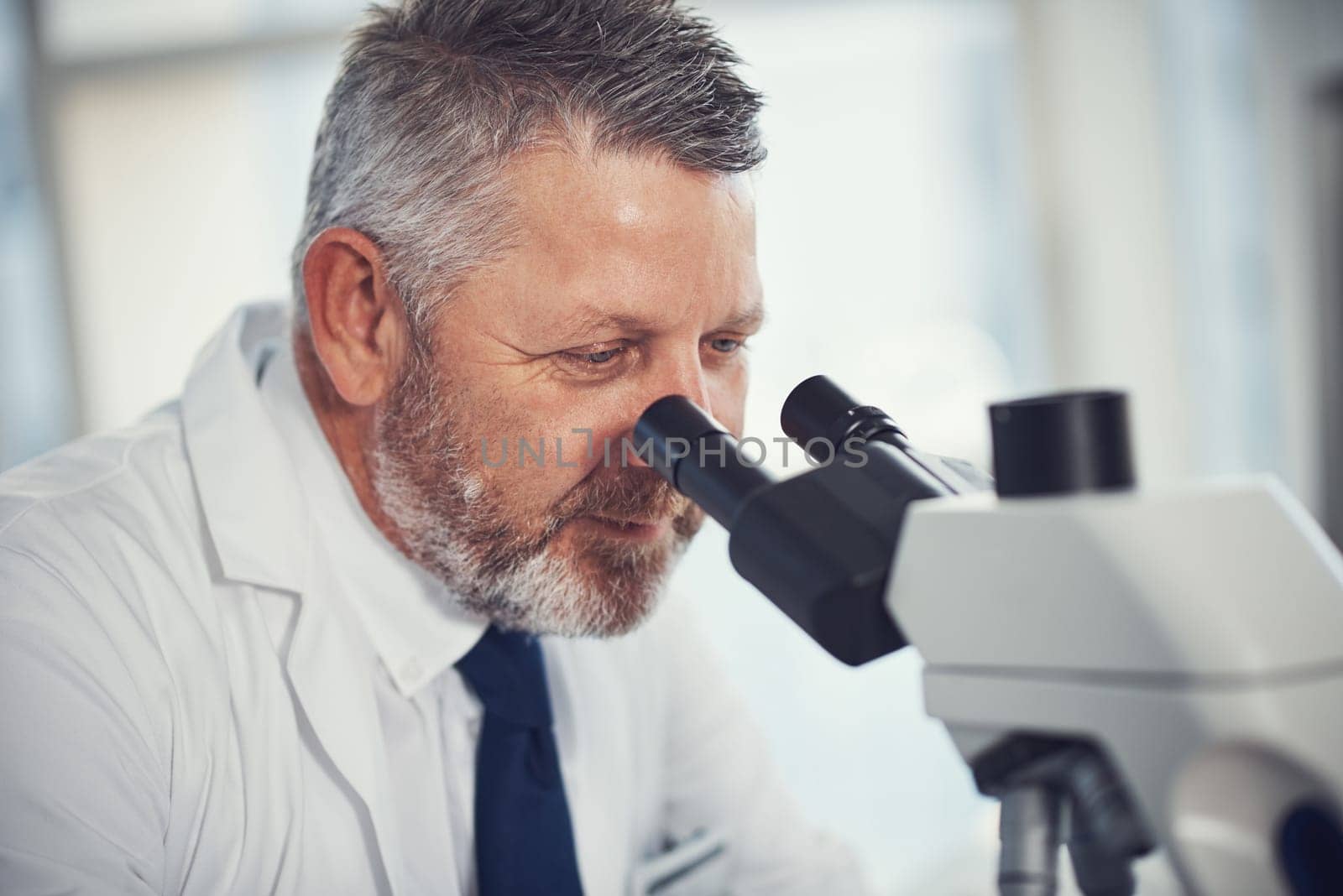 Making medical magic happen. a mature scientist using a microscope in a laboratory. by YuriArcurs