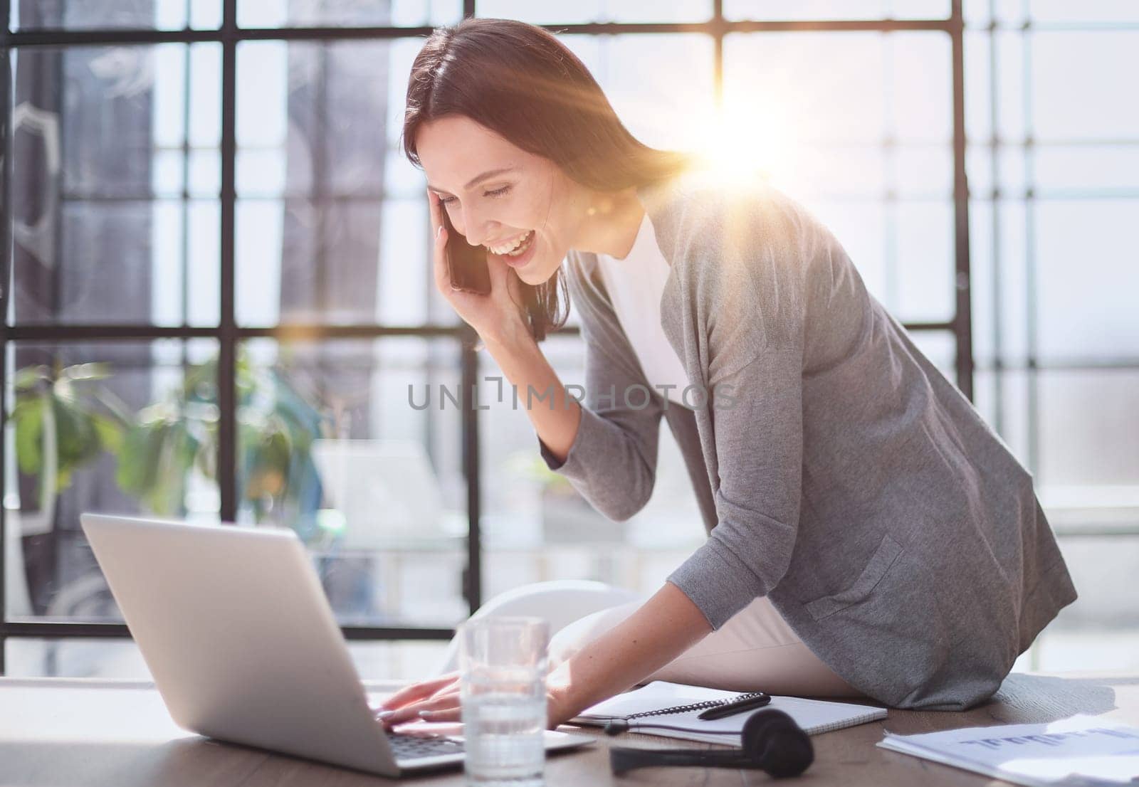 Businesswoman sitting in office, talking on the phone