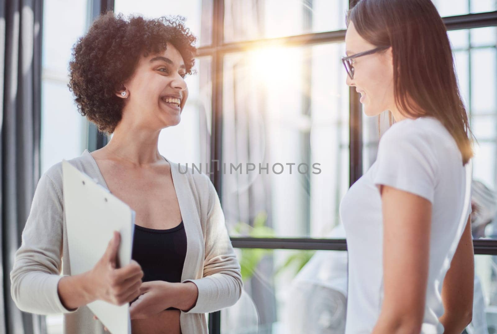 Two middle age beautiful businesswomen smiling happy and confident working together. Shaking hands with smile on face for agreement at the office