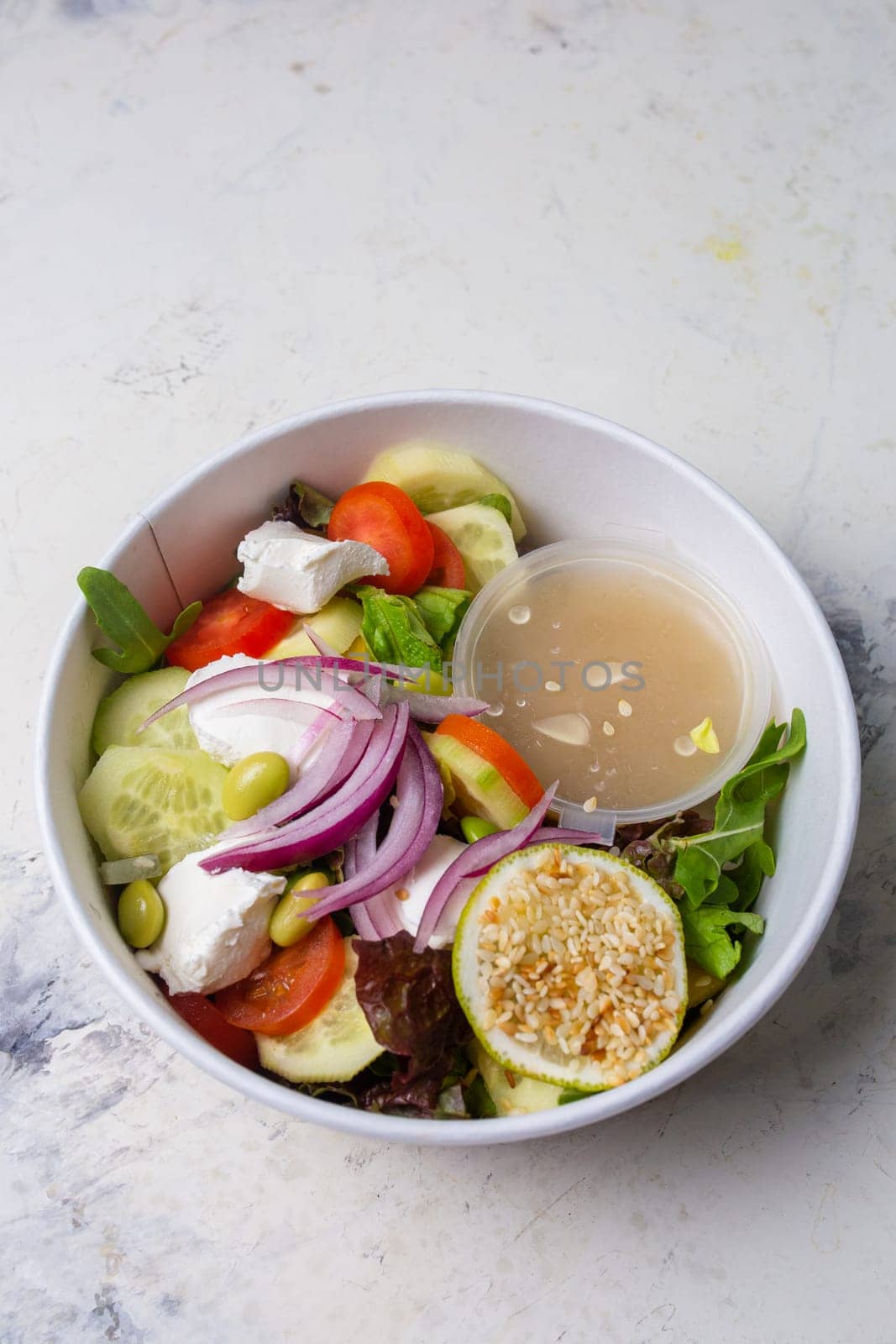 vegetable salad with cheese and sauce on a white background top view.