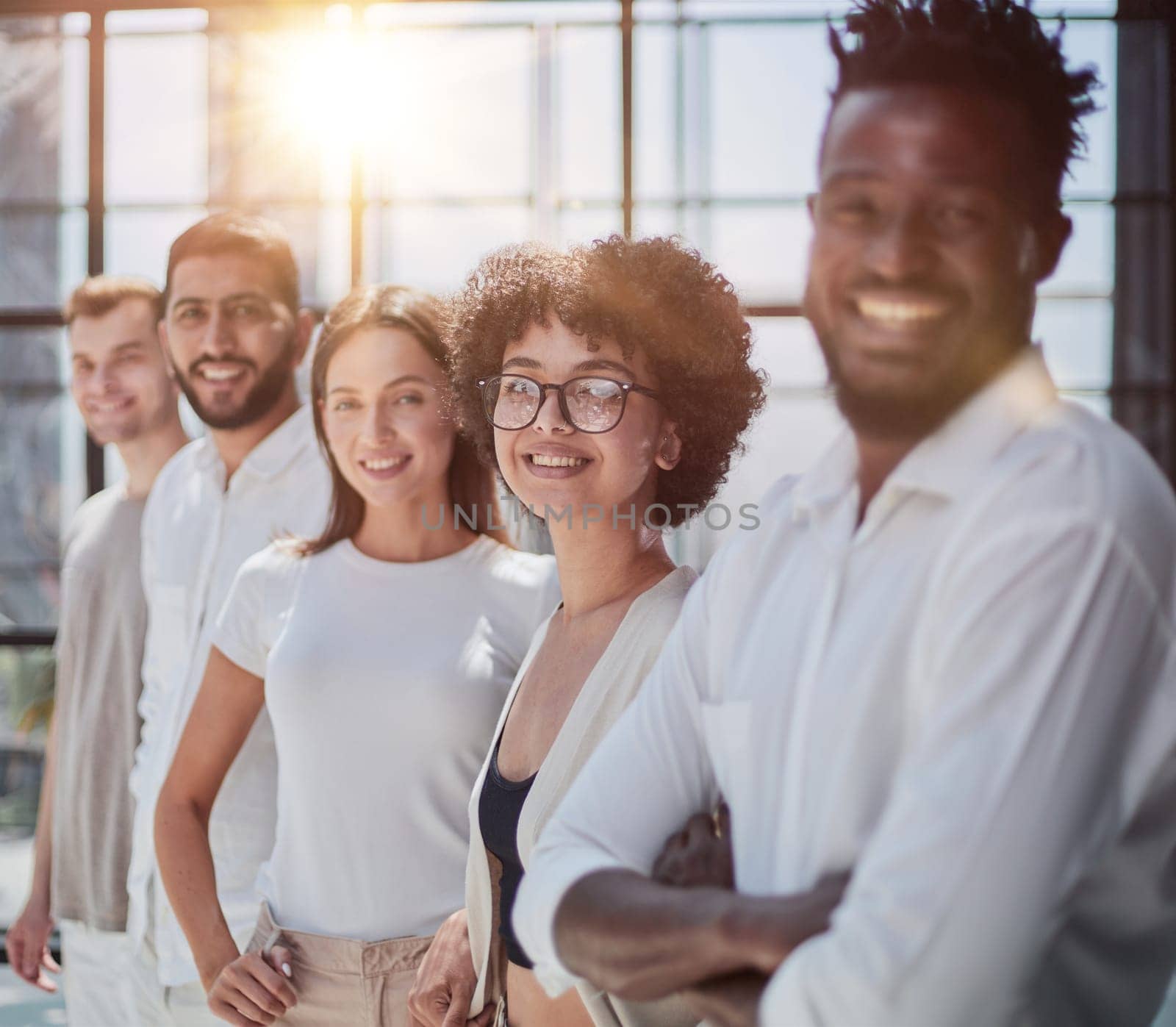 Portrait of smiling African American business man with executives working on laptop in background.