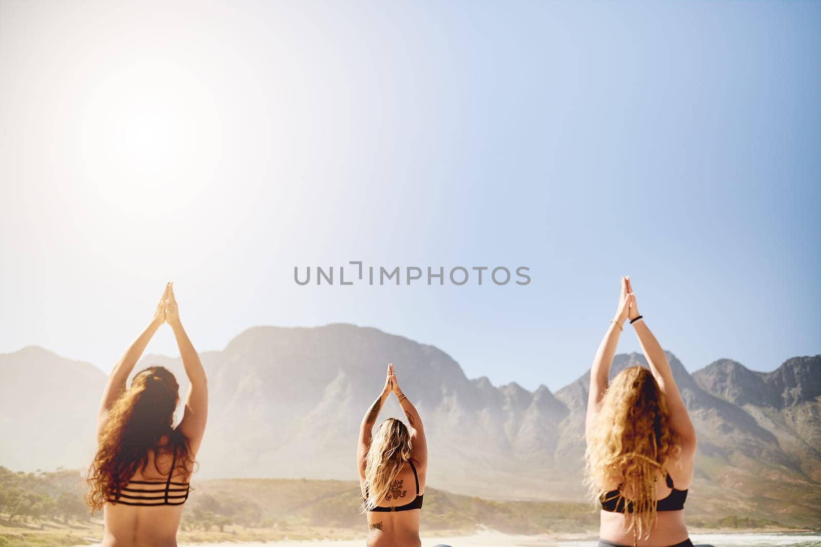 Yoga is always a good idea. Rearview shot of three young women practising yoga on the beach. by YuriArcurs