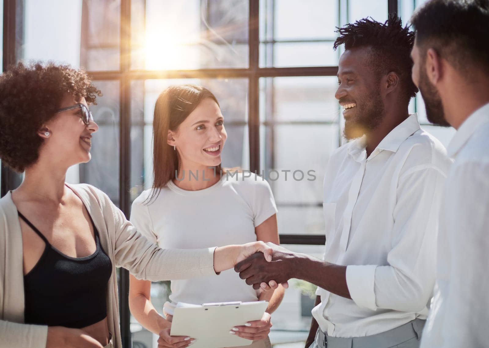 Glad to work with you. Young modern men in smart casual wear shaking hands and smiling while working in the creative office