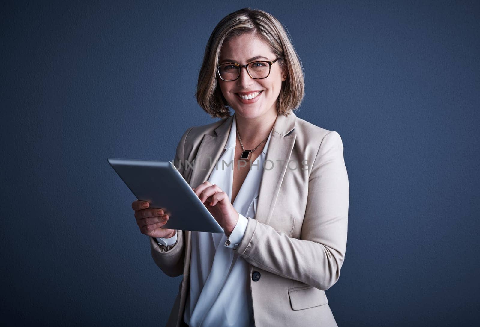 Its an invaluable resource. Studio portrait of an attractive young corporate businesswoman using a tablet against a dark background. by YuriArcurs
