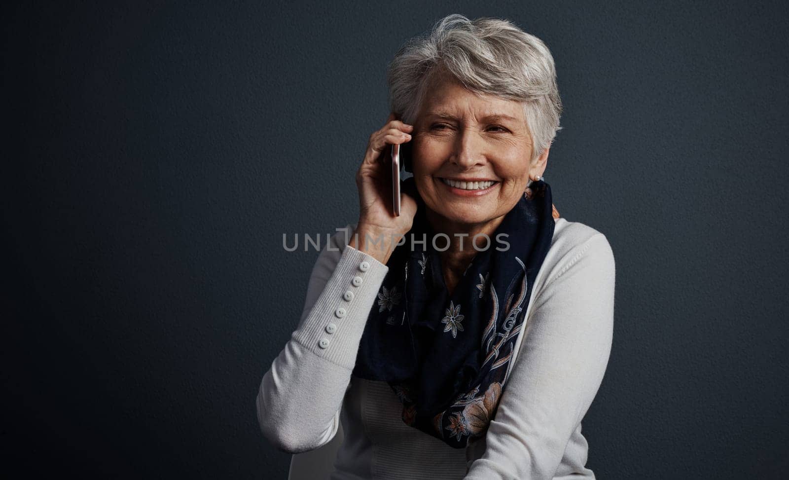 I can talk on this thing the whole day. Studio shot of a cheerful elderly woman sitting down and talking on her cellphone