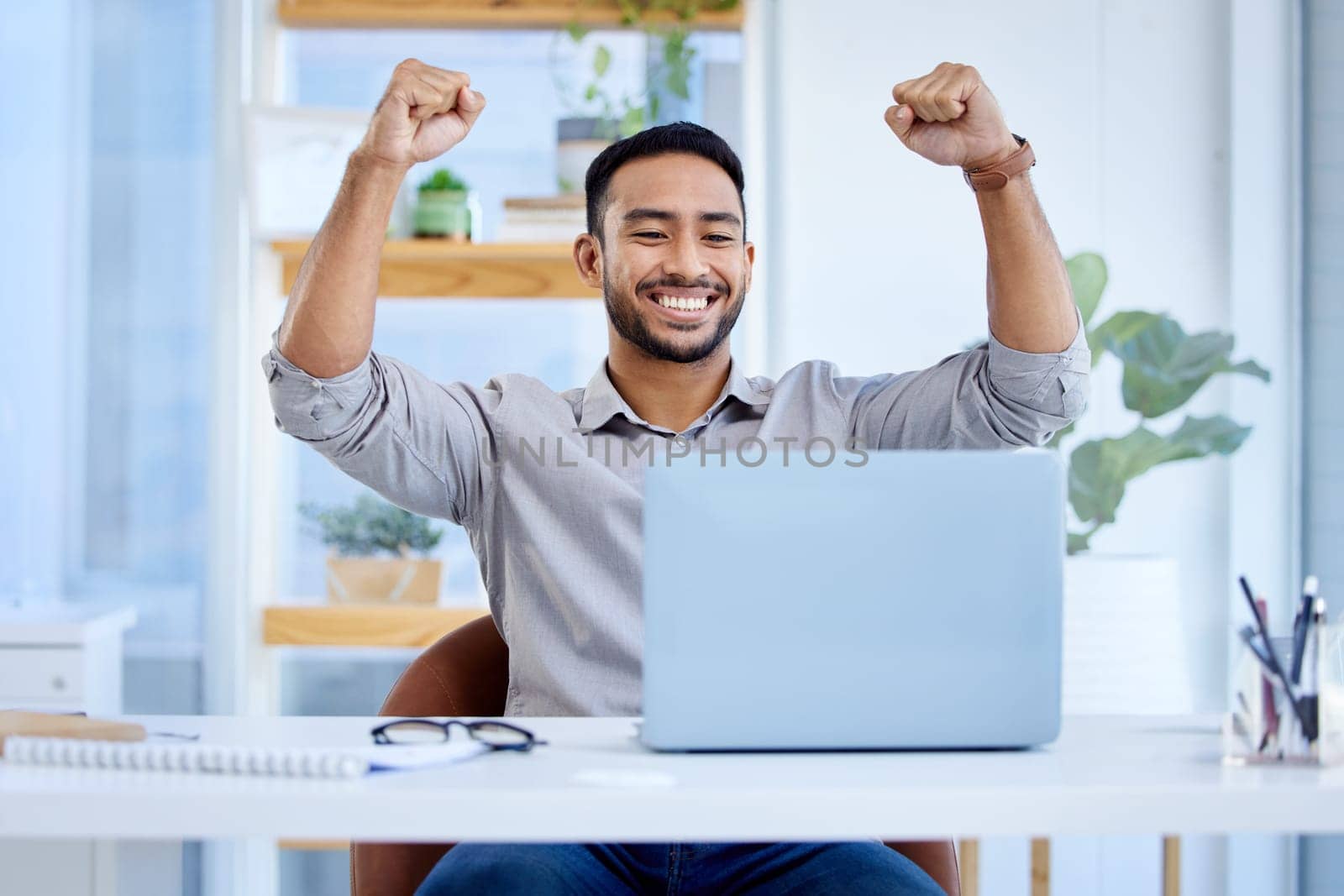 Businessman, laptop and celebrate success or win at desk with fist for bonus deal. Excited Asian man or entrepreneur with tech for profit, competition or online achievement and loan notification by YuriArcurs