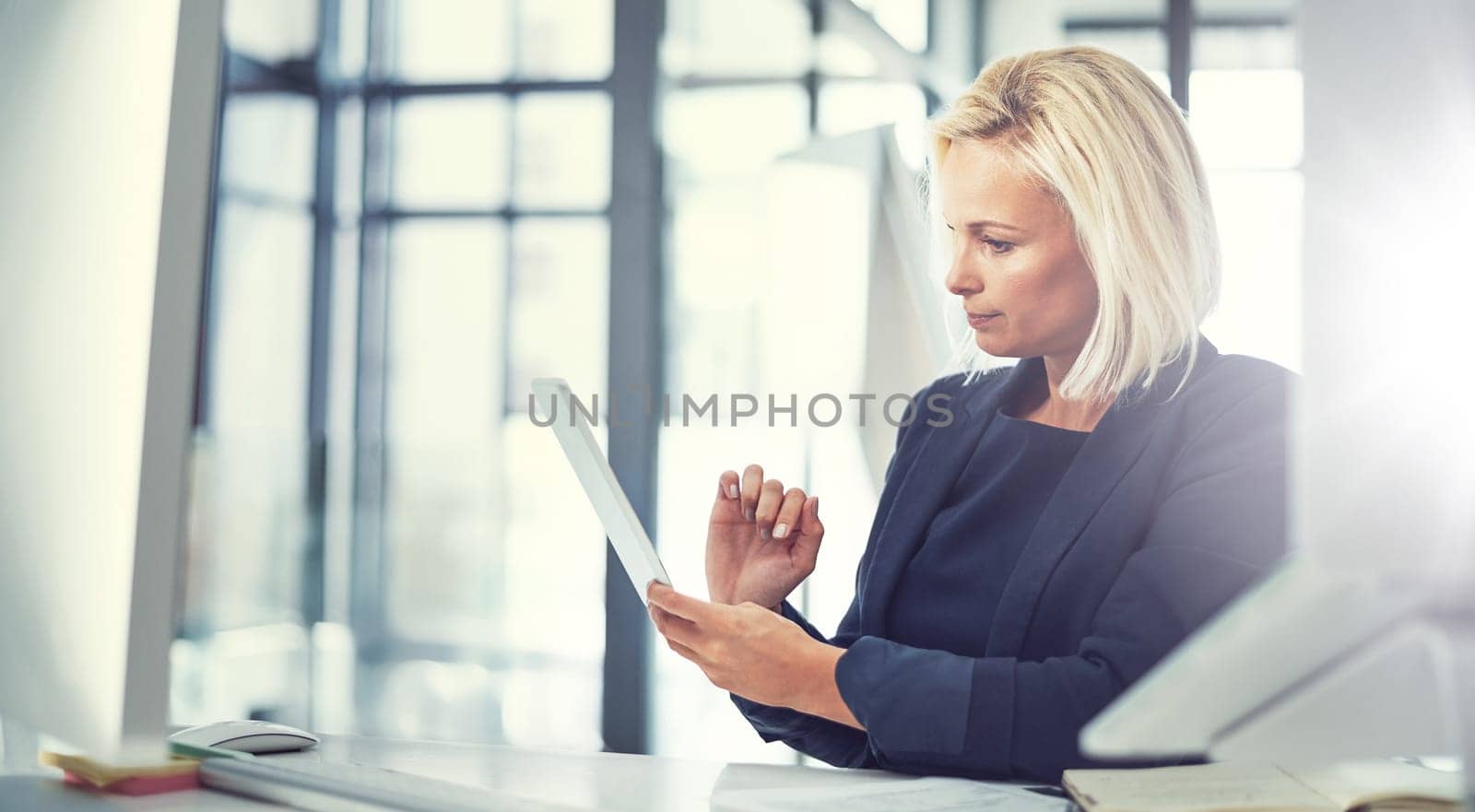 Running her workday on smart technology. a businesswoman using a digital tablet at work. by YuriArcurs