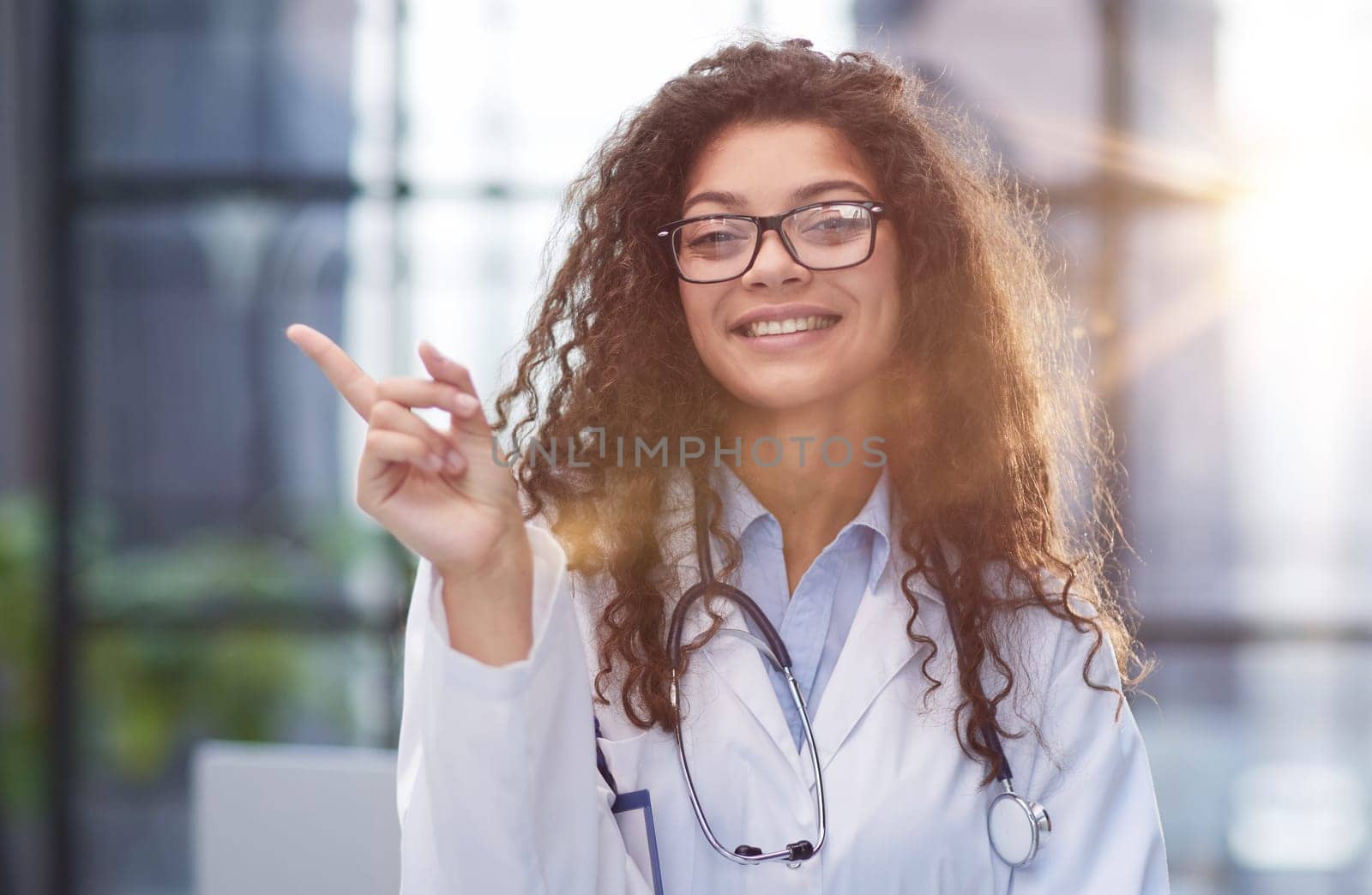 Portrait of an attractive young female doctor in a white coat points her finger