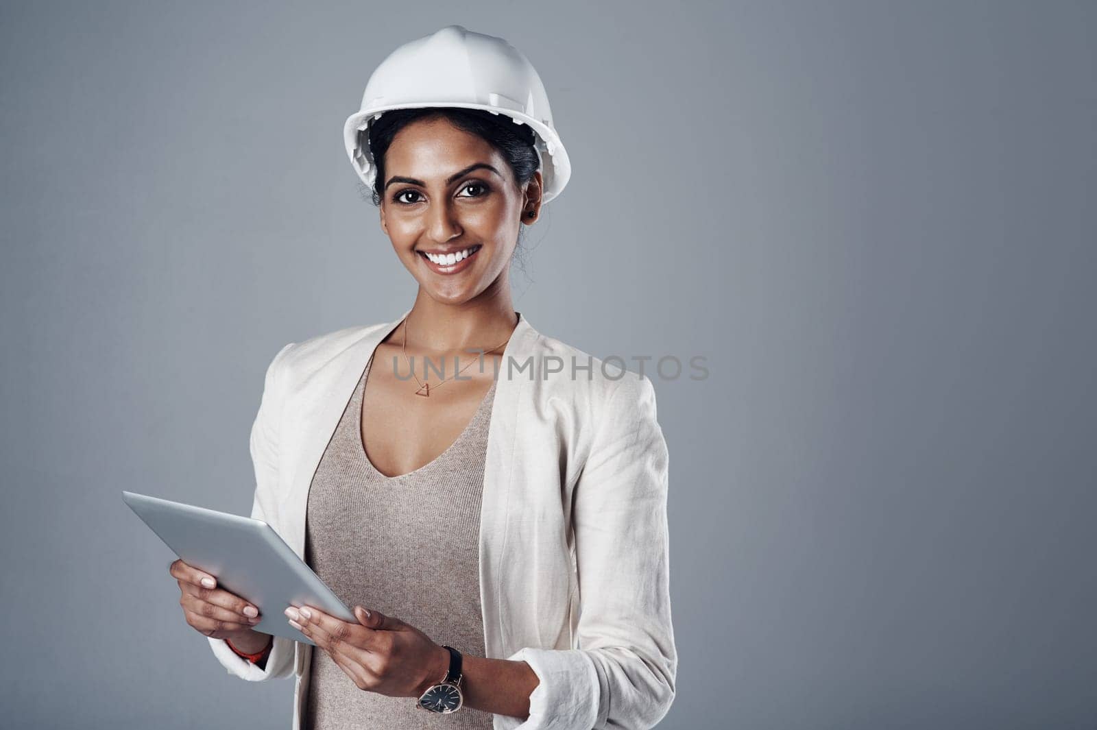 Dream big and build bigger. Portrait of a well-dressed civil engineer using her tablet while standing in the studio. by YuriArcurs