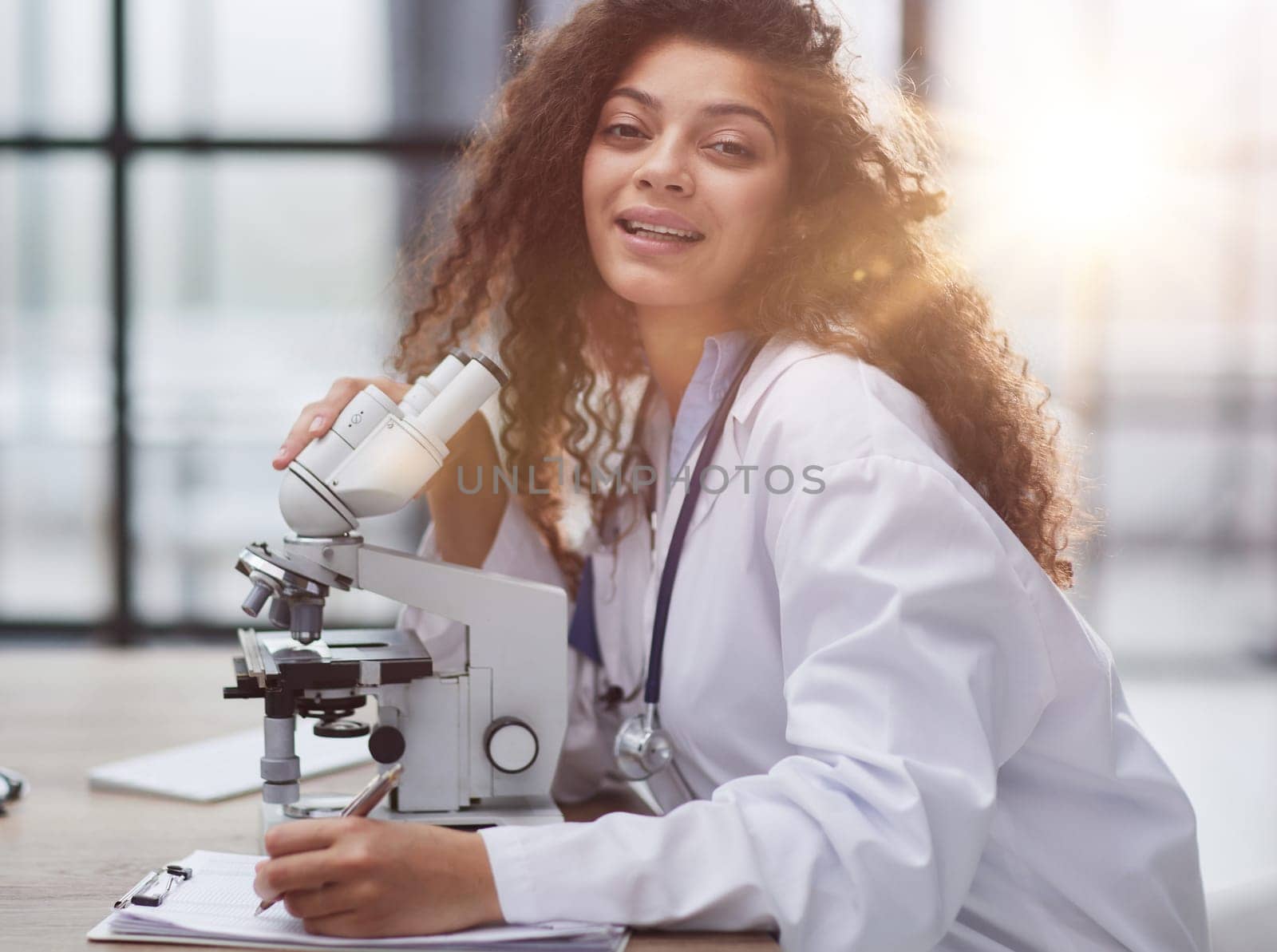 Attractive female scientist looking through a microscope