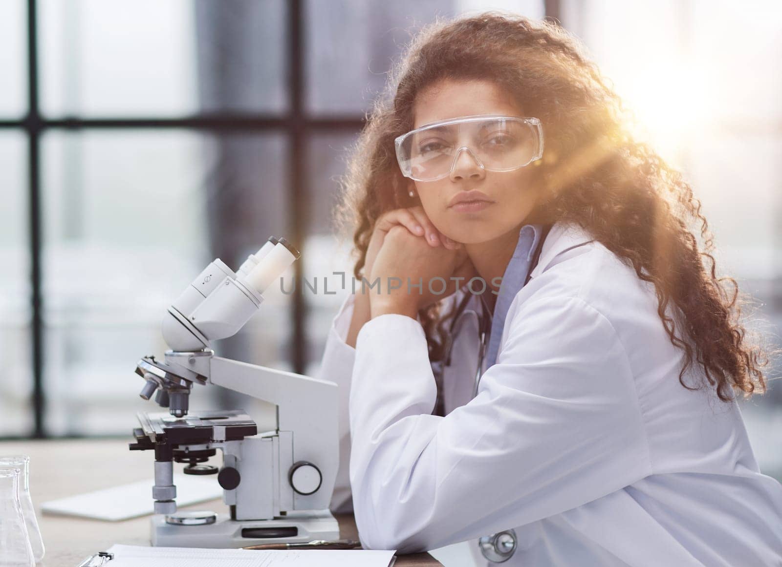 Young woman in biological laboratory. Attractive young female scientis. Scientist using a microscope in a laboratory