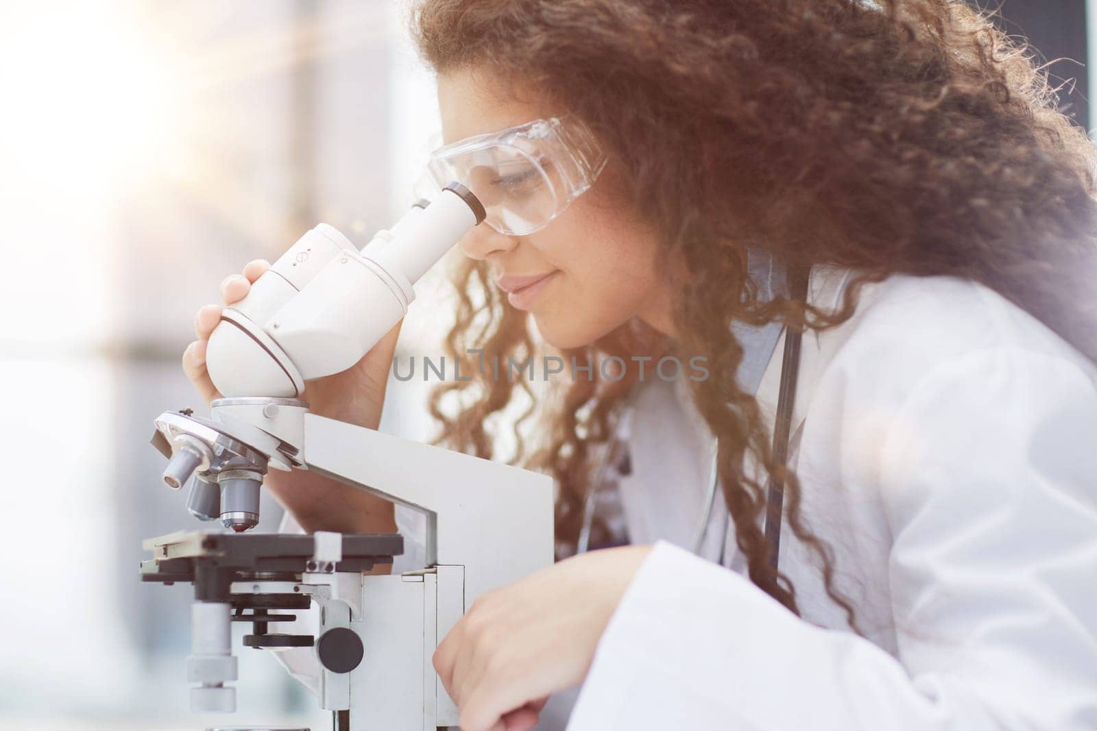 Young woman in biological laboratory. Attractive young female scientis. Scientist using a microscope in a laboratory
