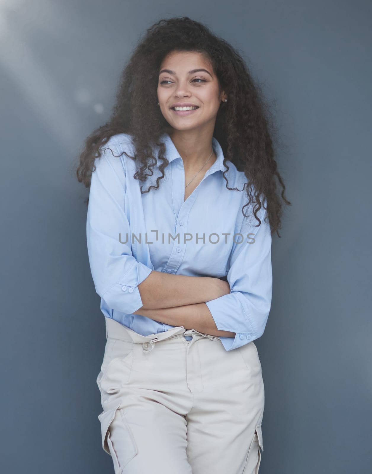 Smiling attractive young business woman in blue shirt posing on gray background by Prosto