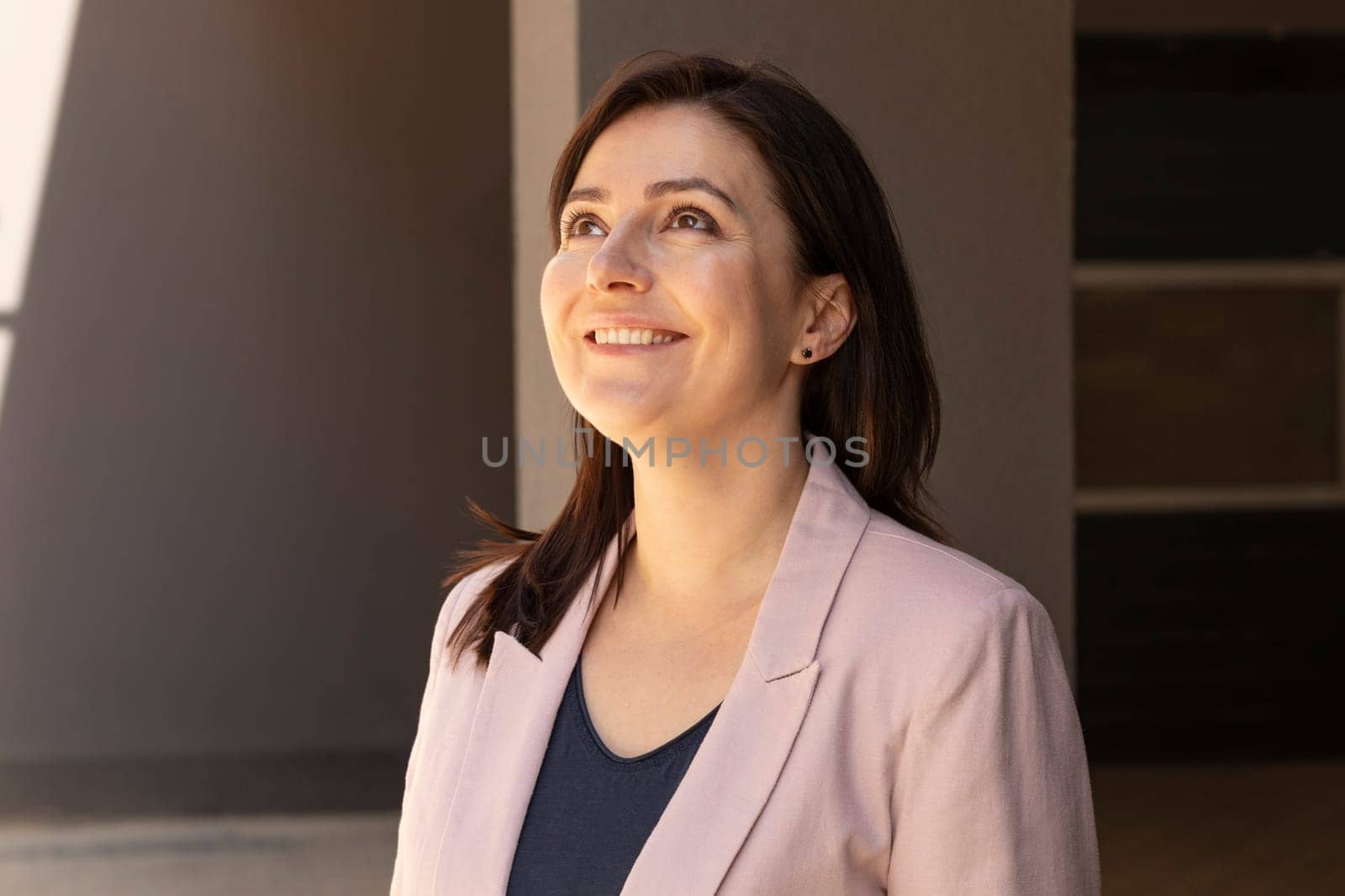 Portrait Happy Mature 40 yo Beautiful Woman Smiling With Teeth. Caucasian Burnette Female With Brown Eyes Looks Up, Wears Pink Jacket, Blue Shirt. Horizontal Plane. High quality photo