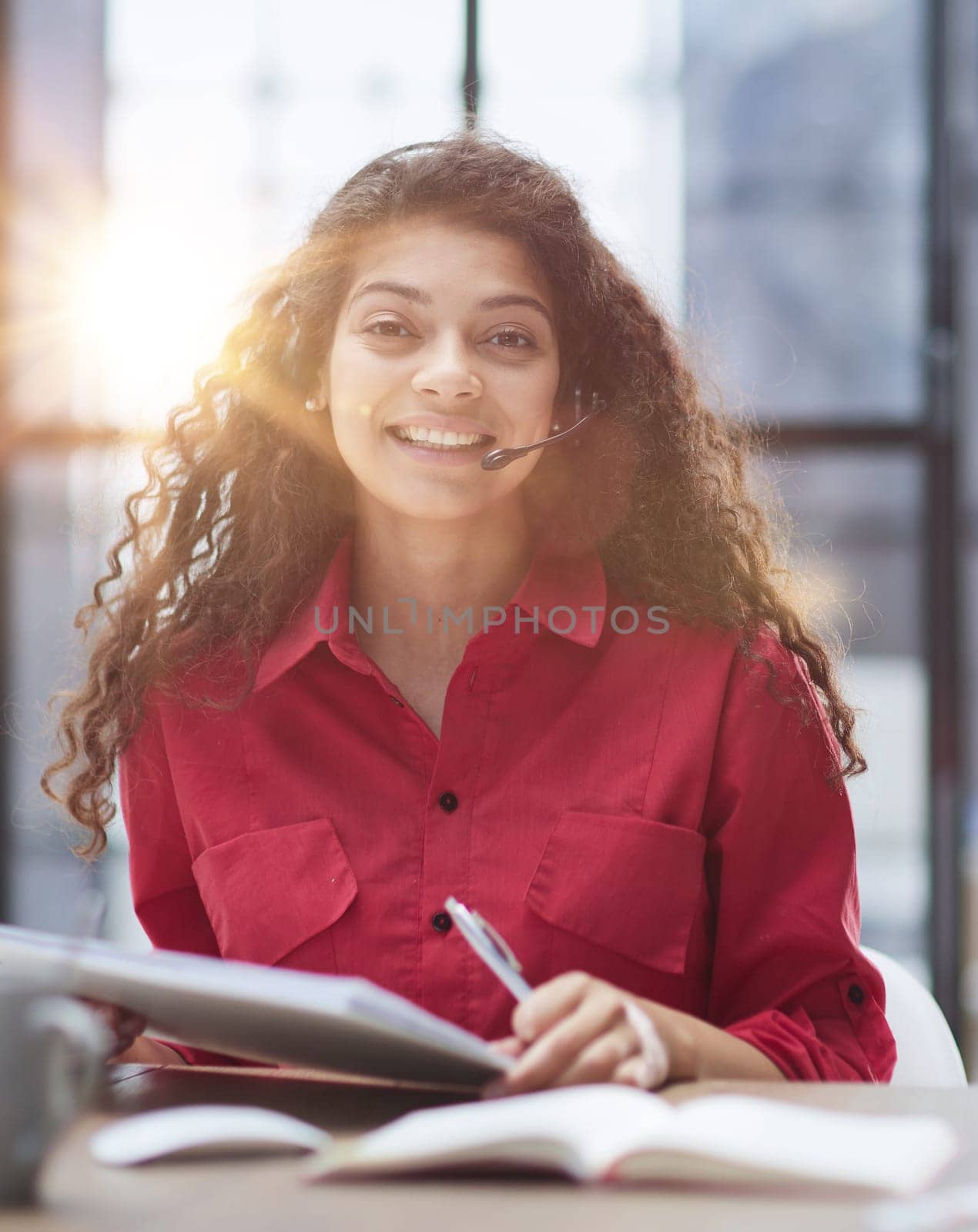 Attractive young business woman, writing notes to notebook at her workplace in office.