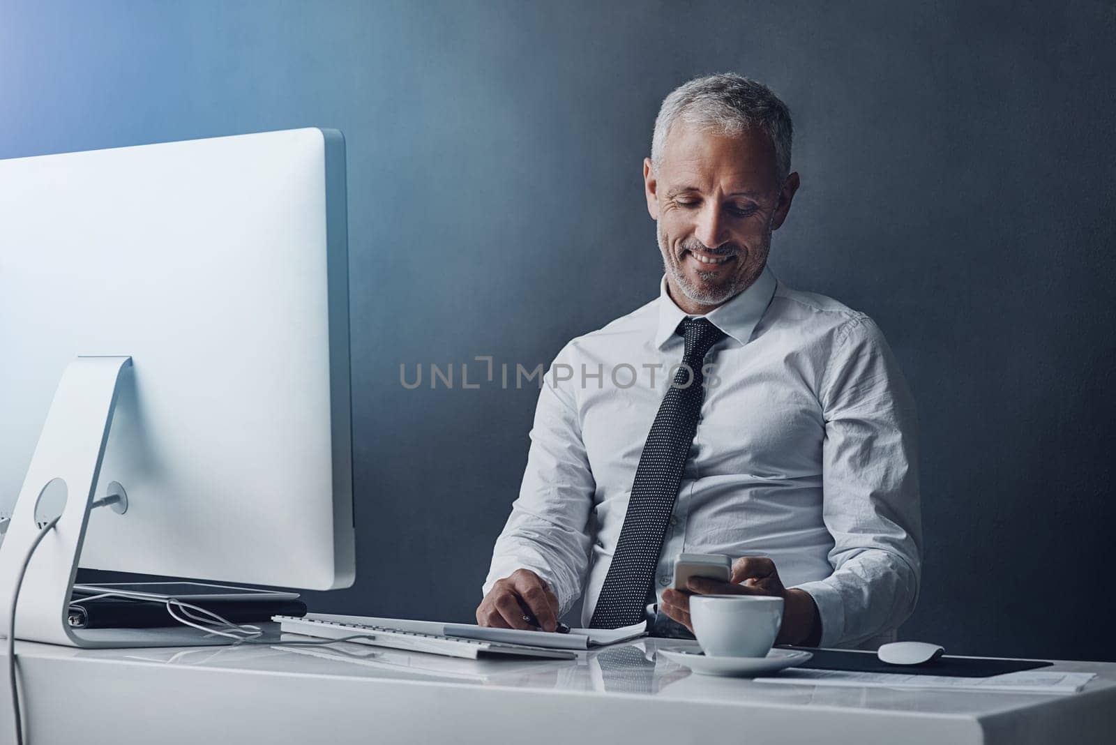 Ill be home soon. a mature businessman sending a text while working on his computer